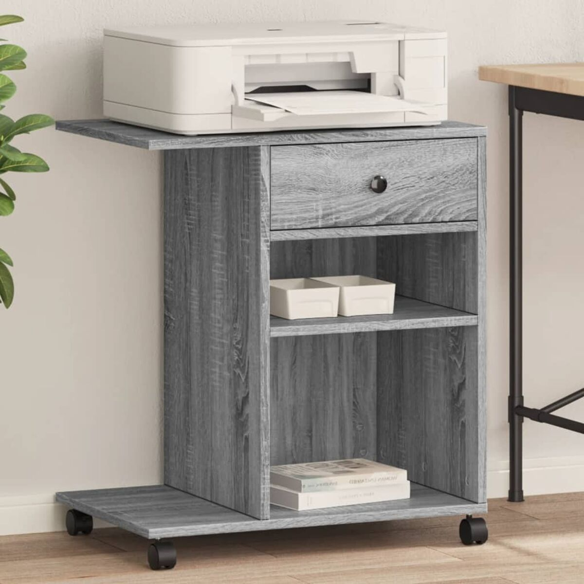 Ein grauer Schrank auf Rädern mit Drucker, Schublade und Regalen. Es gibt zwei Boxen.