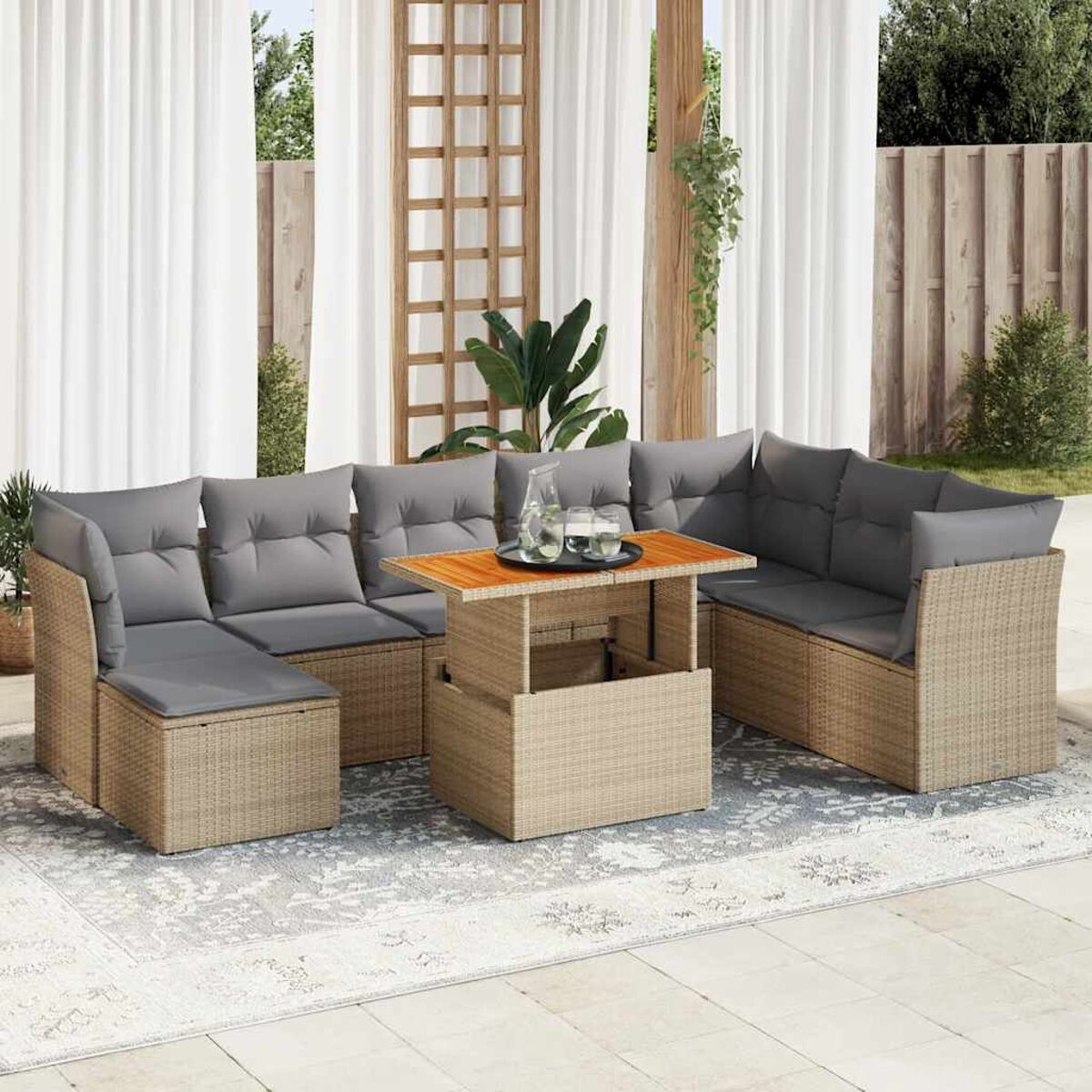 Set divano in rattan da esterno con cuscini grigi e tavolo sollevabile, su un patio, con tenda bianca.