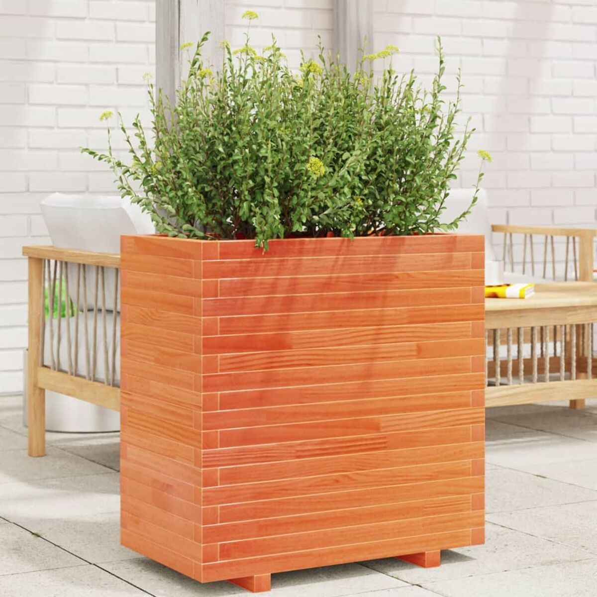 Oranger Holzpflanzkasten mit grüner Pflanze. Hintergrund Ziegelmauer, Terrasseneinstellung.