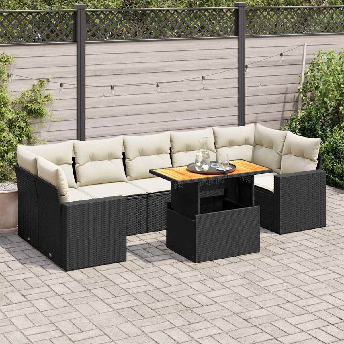 Set da patio all'aperto. Mobili in vimini neri, include un tavolo e un divano componibile con cuscini.