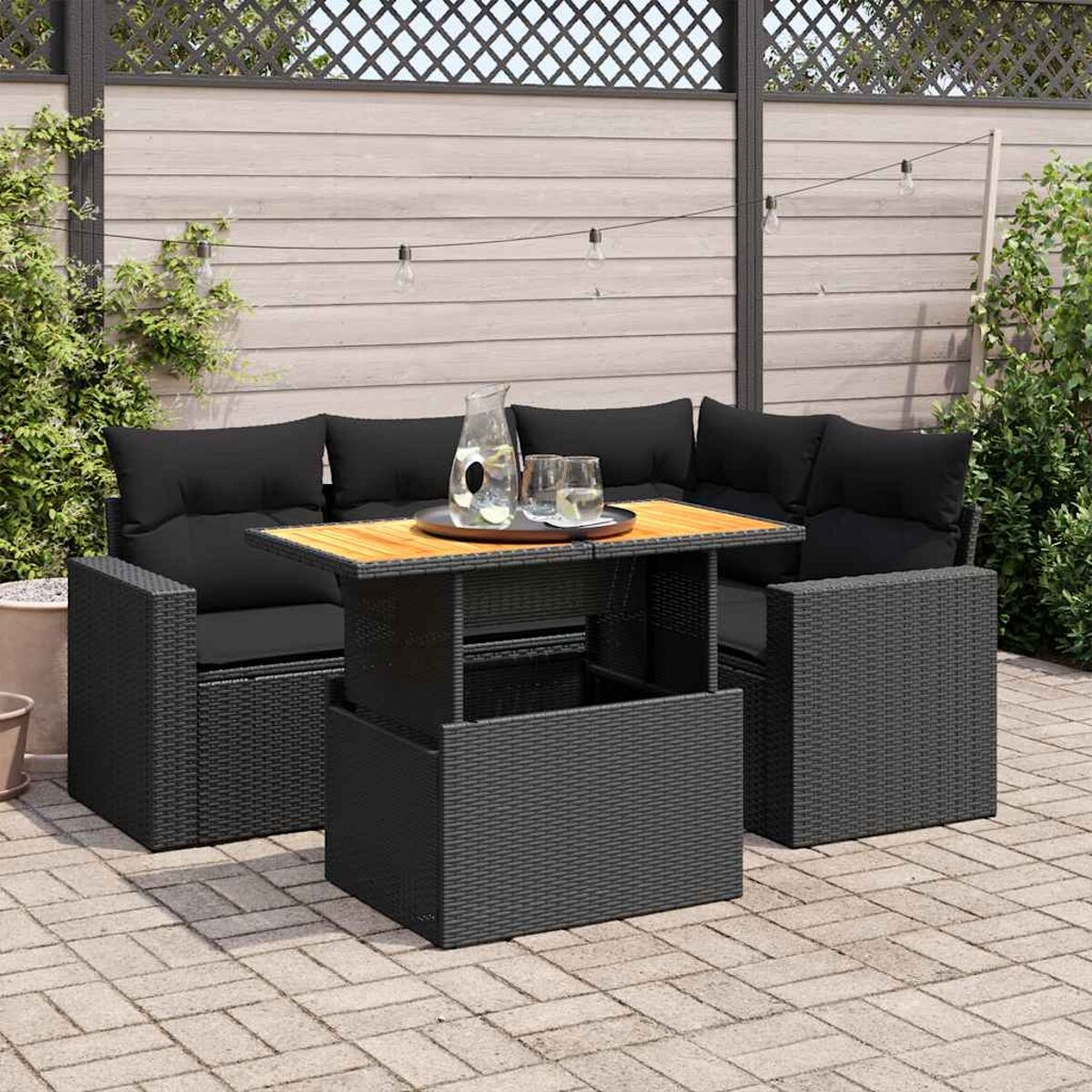 Un set da patio esterno nero con un tavolo e un'area salotto. C'è un piano del tavolo in legno.