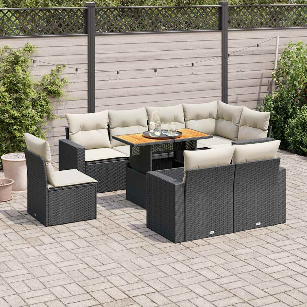 Set divani neri da esterno con tavolo. Piano del tavolo in legno, cuscini beige.