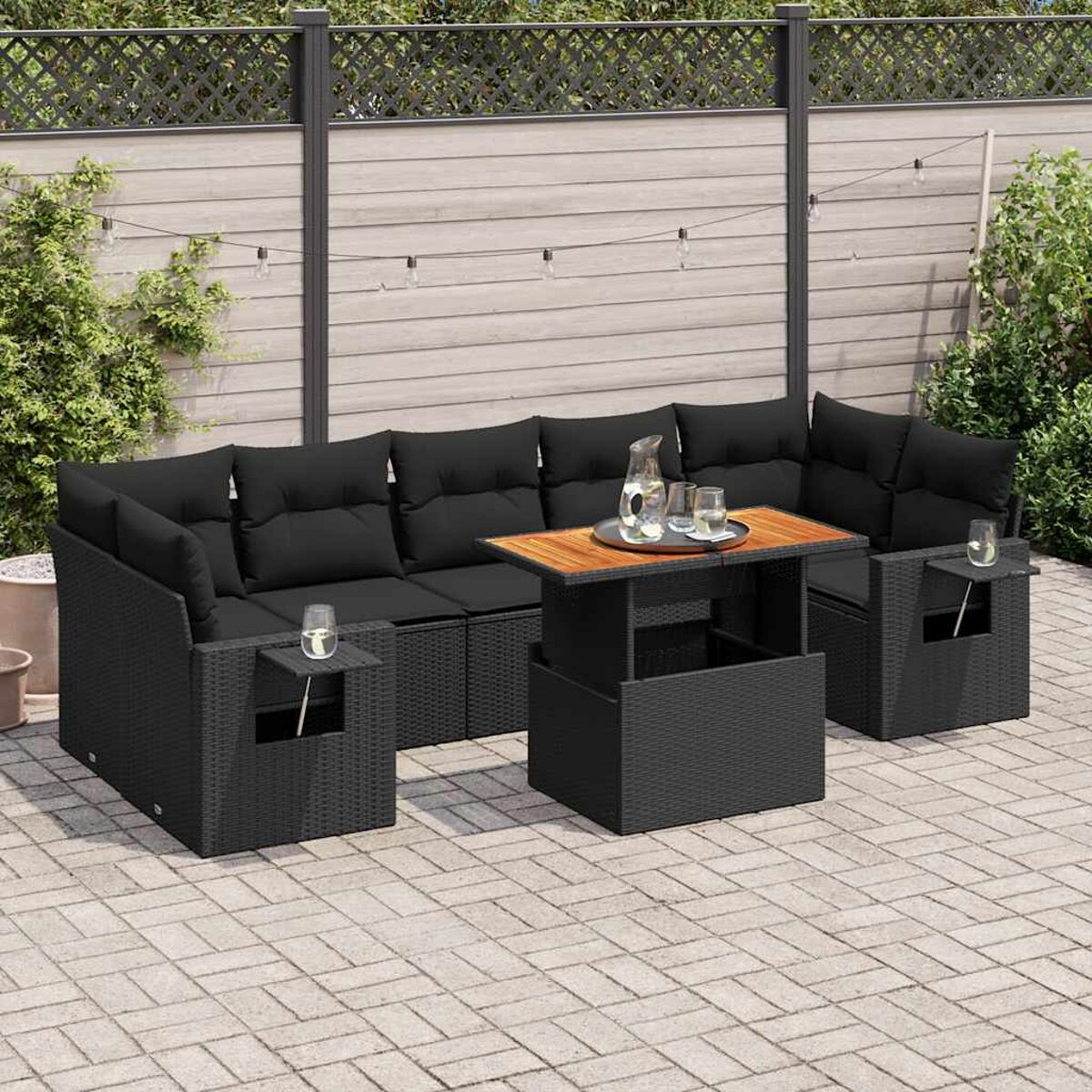 Set di mobili da esterno in vimini nero con cuscini neri, tavolo e bevande.