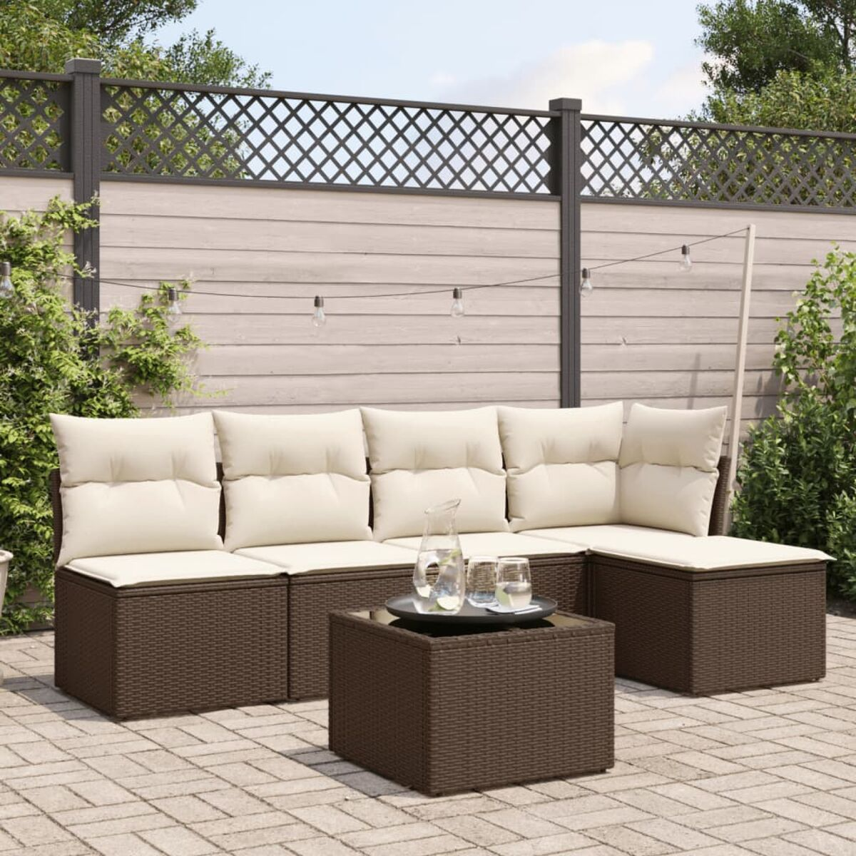 Set divani da esterno in vimini marrone con cuscini color crema, tavolo.