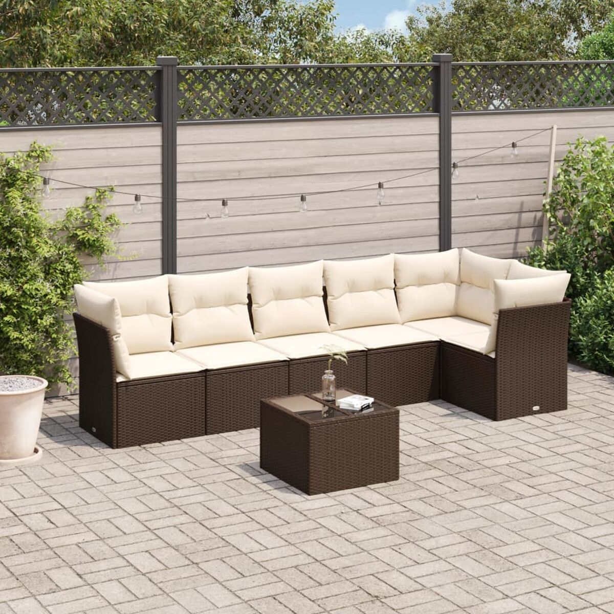 L-förmiges braunes Outdoor-Sofa aus Korbgeflecht mit cremefarbenen Kissen und einem passenden Couchtisch.