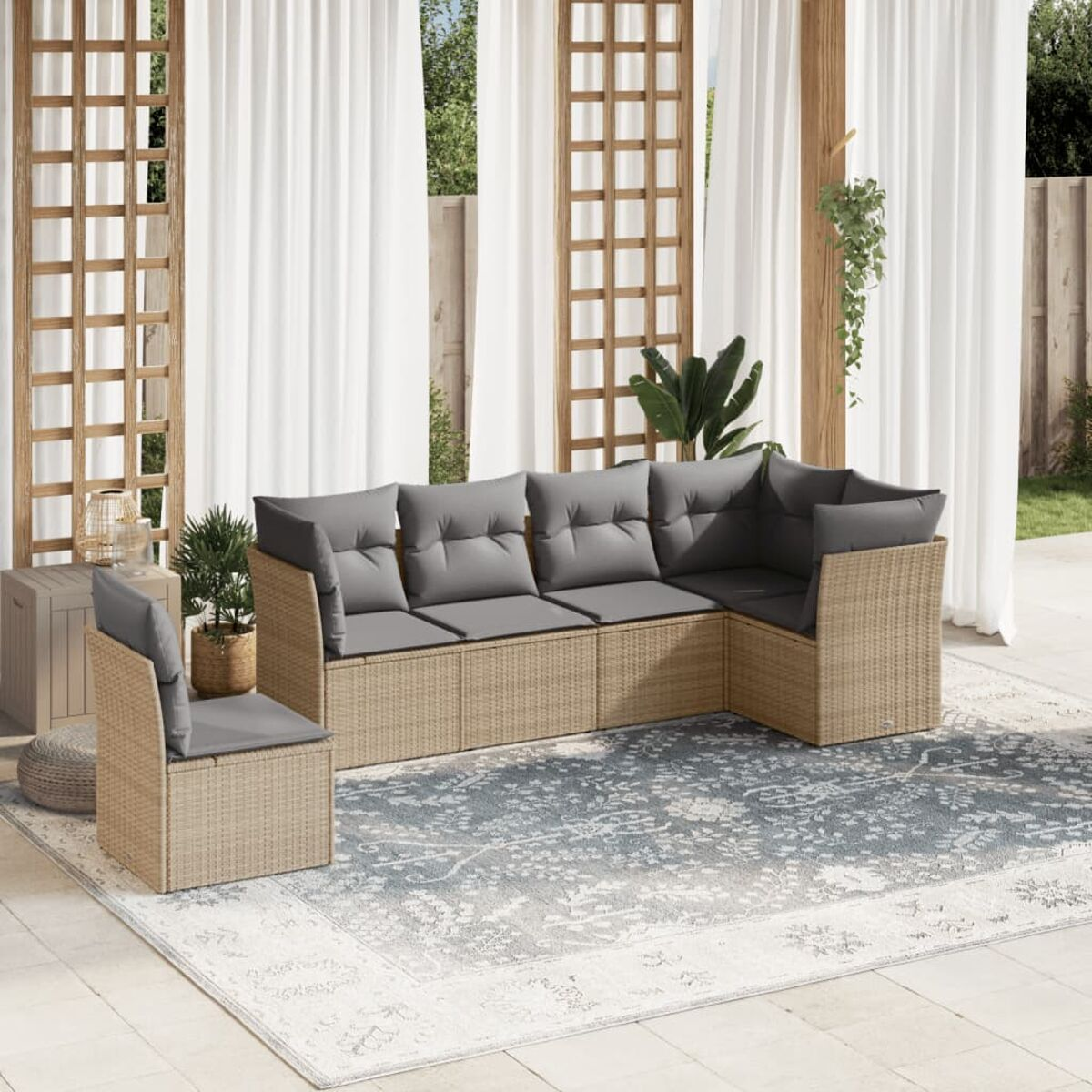 Rattan-Gartensektionssofa mit grauen Kissen, einem einzelnen Stuhl und einem Teppich. Weiße Vorhänge im Hintergrund.