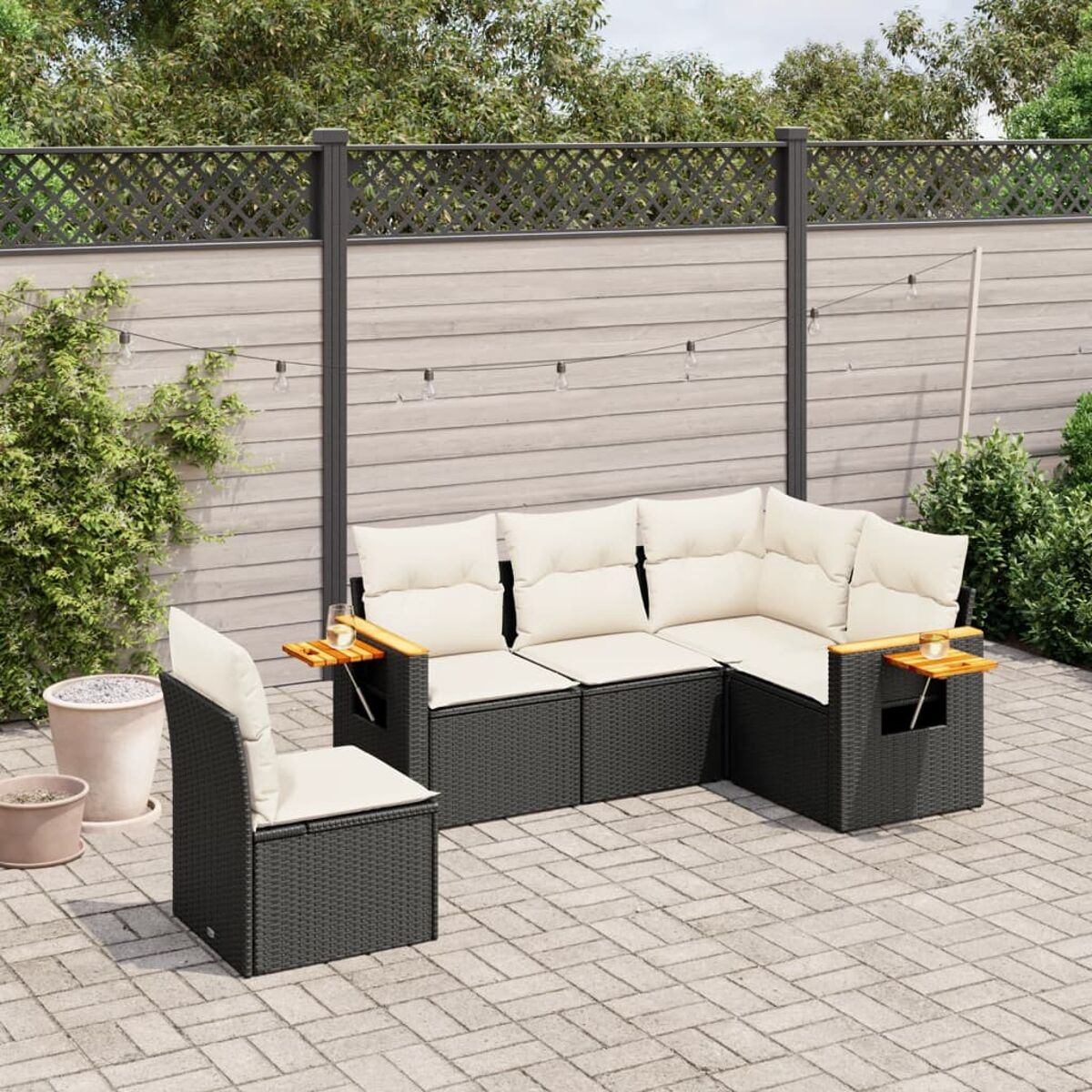 Schwarzes Outdoor-Sofa aus Korbgeflecht mit weißen Kissen und Beistelltischen.