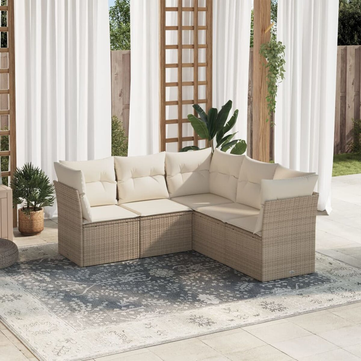 Outdoor-Wicker-Ecksofa mit beigen Kissen auf einem gemusterten Teppich. Weiße Vorhänge im Hintergrund.