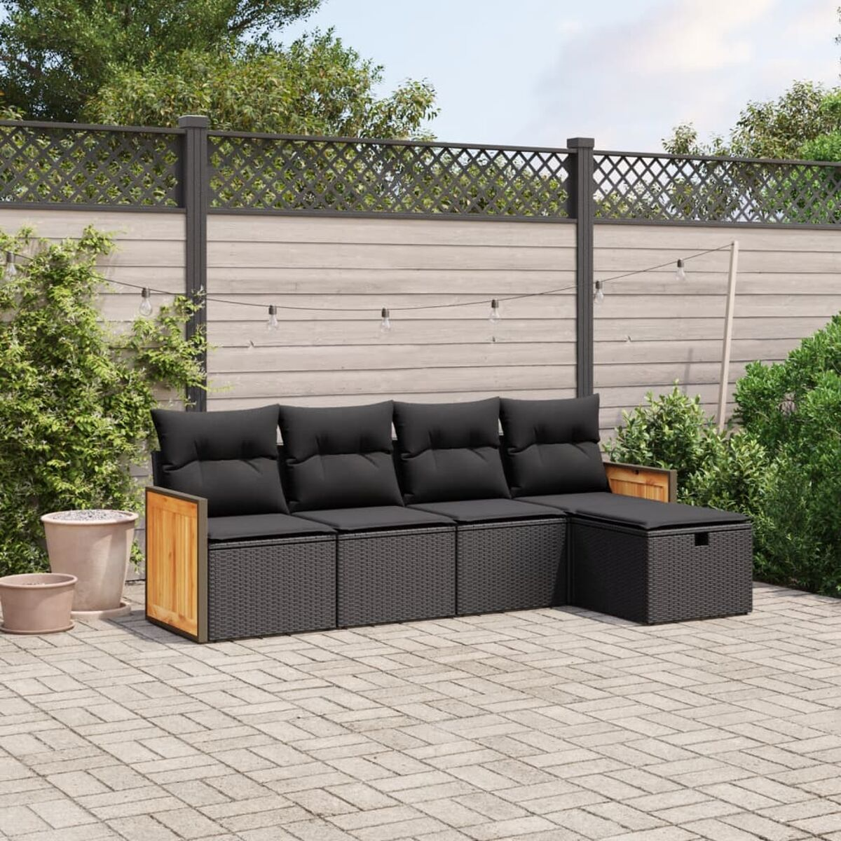 Outdoor-Ecksofa mit schwarzen Kissen und grauem Rattan-Gestell. Holzakzente und Backstein-Terrasse.