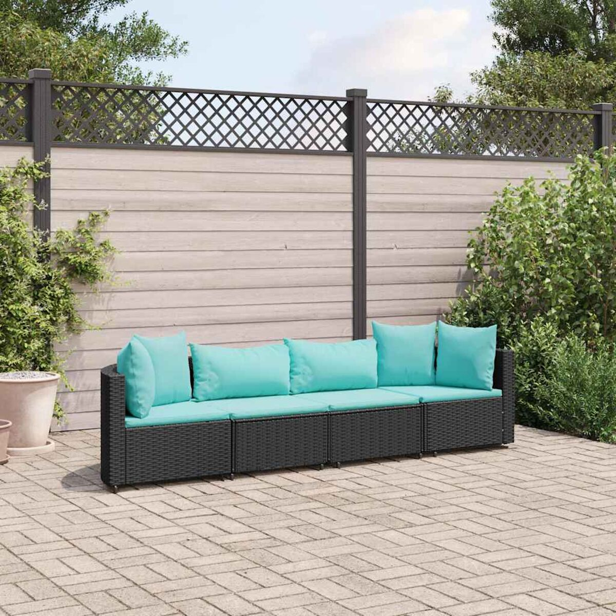 Schwarzes Outdoor-Sofa aus Korbgeflecht mit türkisfarbenen Kissen. Der Hintergrund umfasst einen Zaun und Pflanzen.