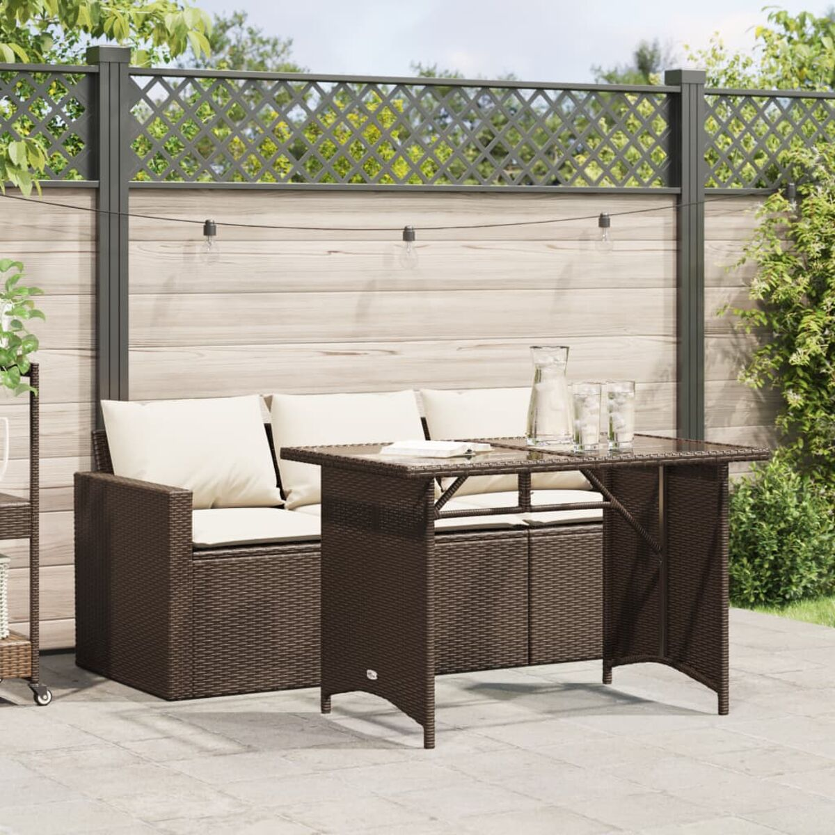 Braunes Korbgeflecht-Gartenmöbel-Set mit Tisch und Sofa, Holzzaun im Hintergrund.