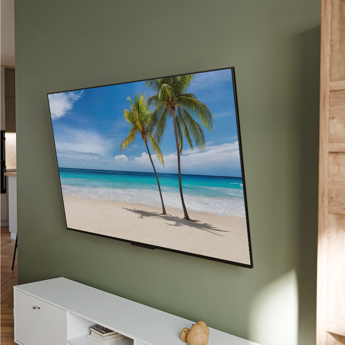 TV murale sur mur vert, affichant une scène de plage avec des palmiers.
