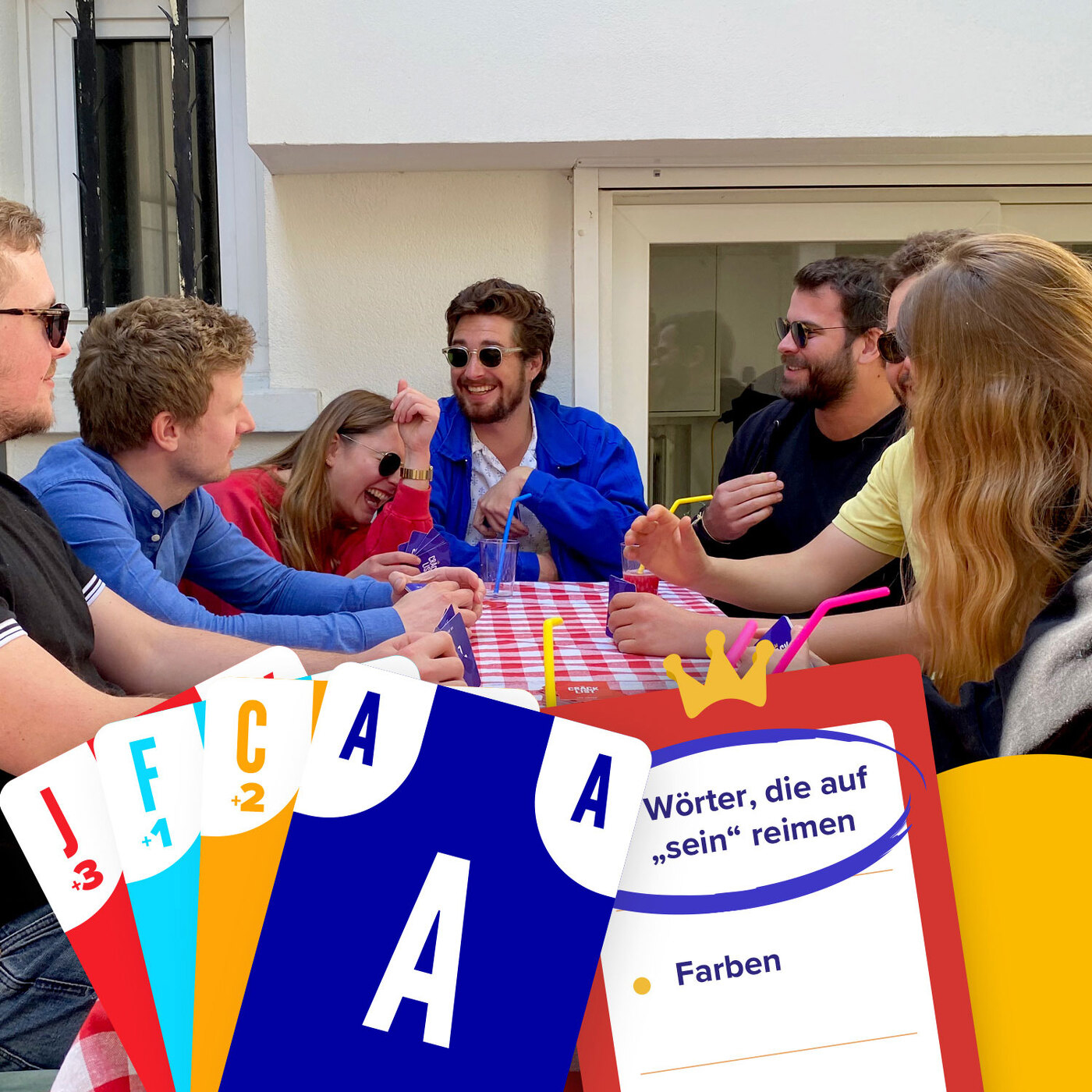 Groupe de personnes jouant aux cartes en extérieur. Cartes sur une table à carreaux rouge et blanc.