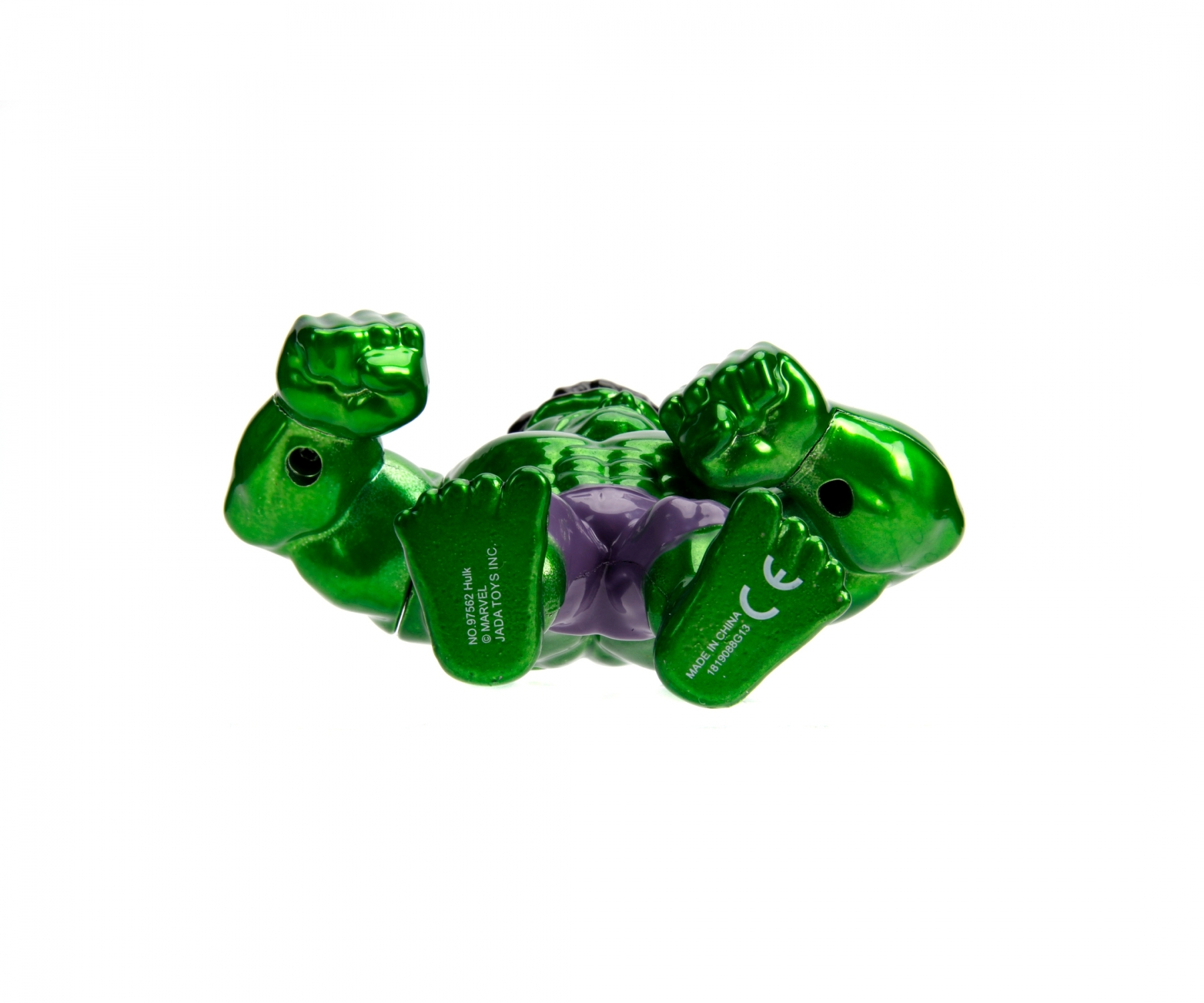 Juguete verde de Hulk tumbado sobre una superficie blanca. El juguete tiene pantalones cortos morados.