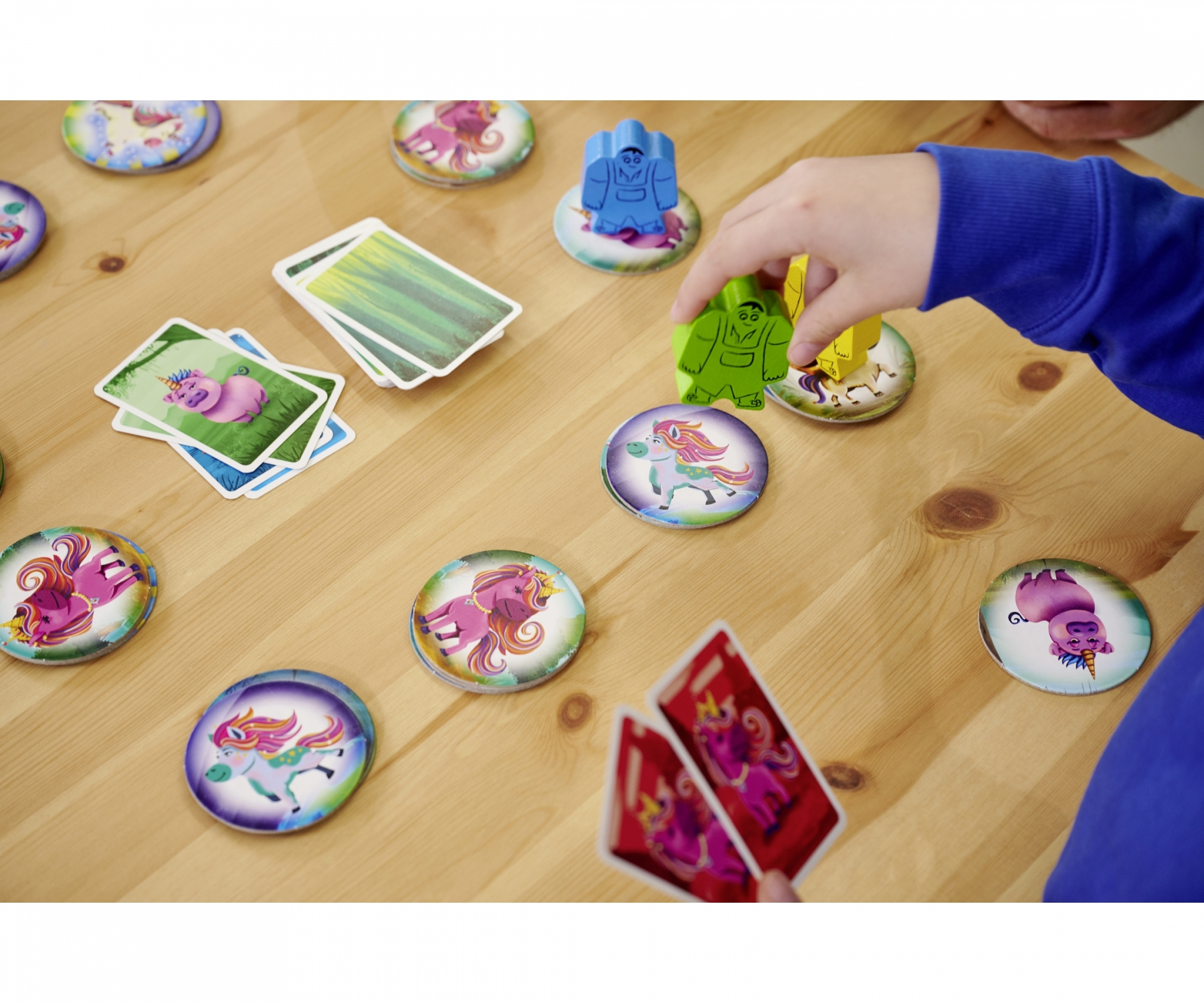 Kinderhand, die ein Brettspiel mit Karten und Spielsteinen spielt.