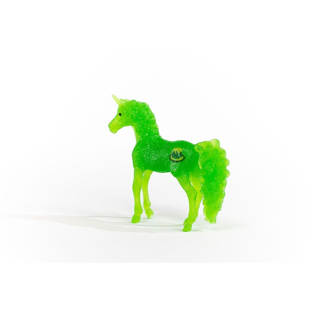 Grünes Einhorn-Spielzeug mit Logo an der Seite, steht auf weißer Oberfläche.