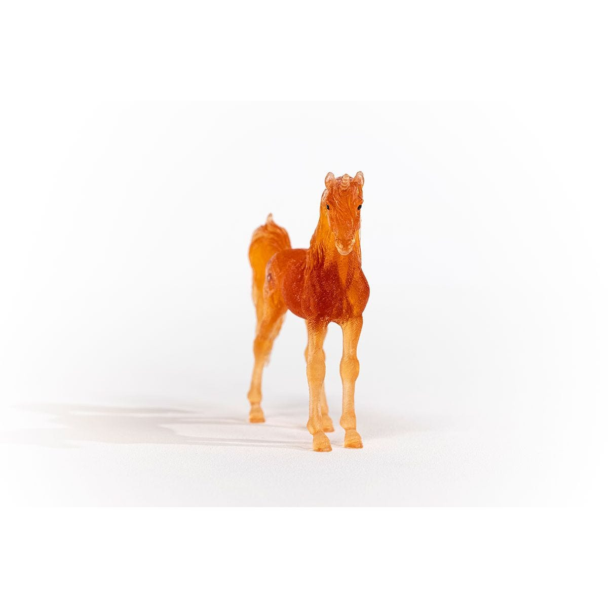 Orangebraunes Spielzeugpferd auf weißem Hintergrund. Das Pferd steht und blickt nach vorne.