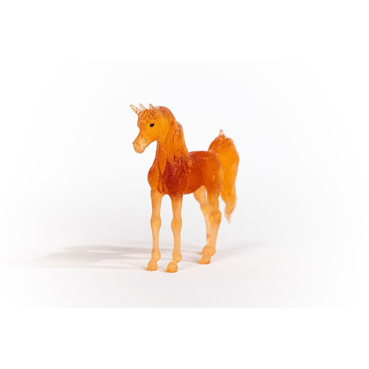 Ein Spielzeug-Einhorn mit orangefarbenem Körper und Horn. Es steht auf einer weißen Oberfläche.