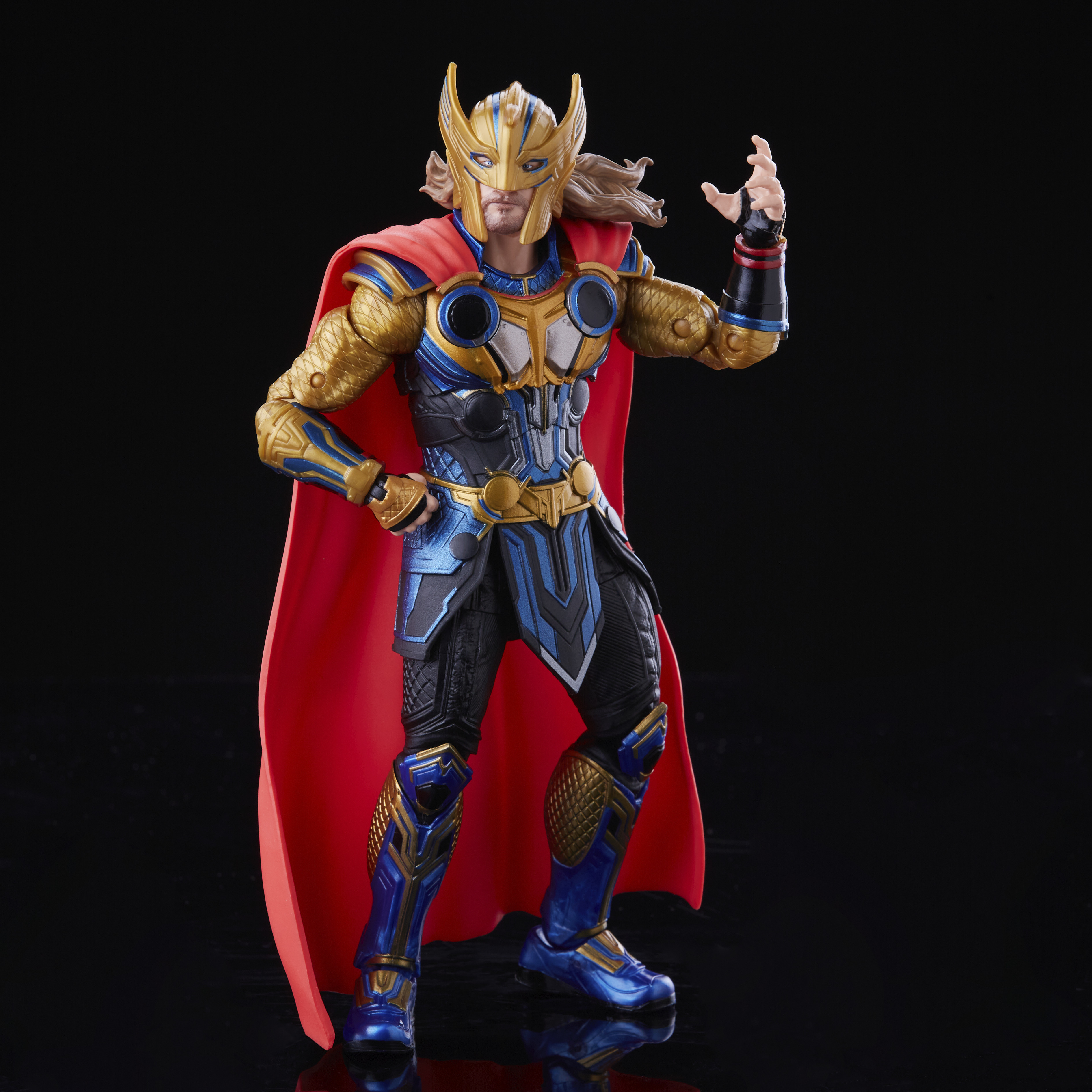 Action figure di Thor con armatura oro e blu, mantello rosso, su superficie nera.