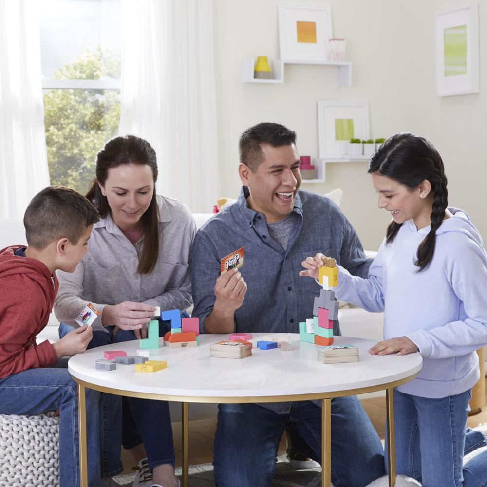 Familie spielt ein Spiel. Personen sitzen an einem Tisch. Blöcke werden gestapelt. Sie lächeln.