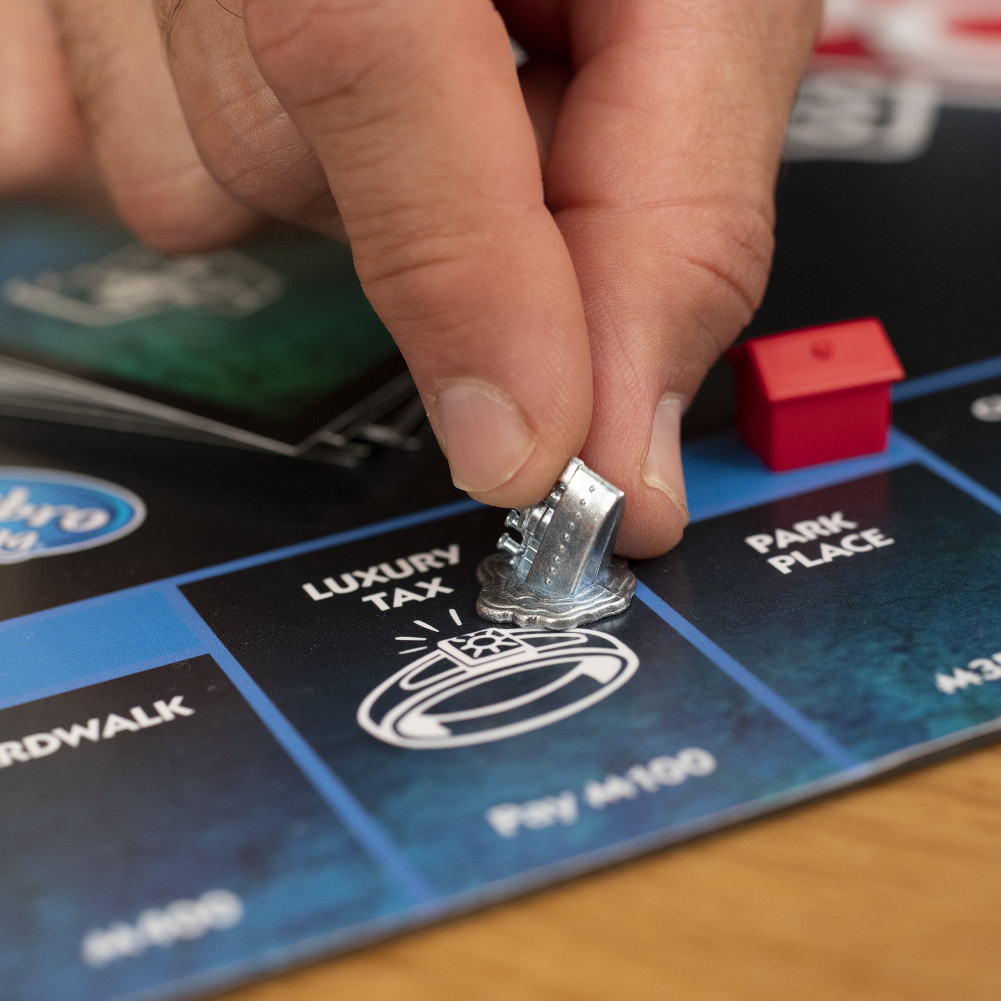 Eine Hand, die eine Monopoly-Spielfigur auf einem Brett mit Luxussteuer platziert.