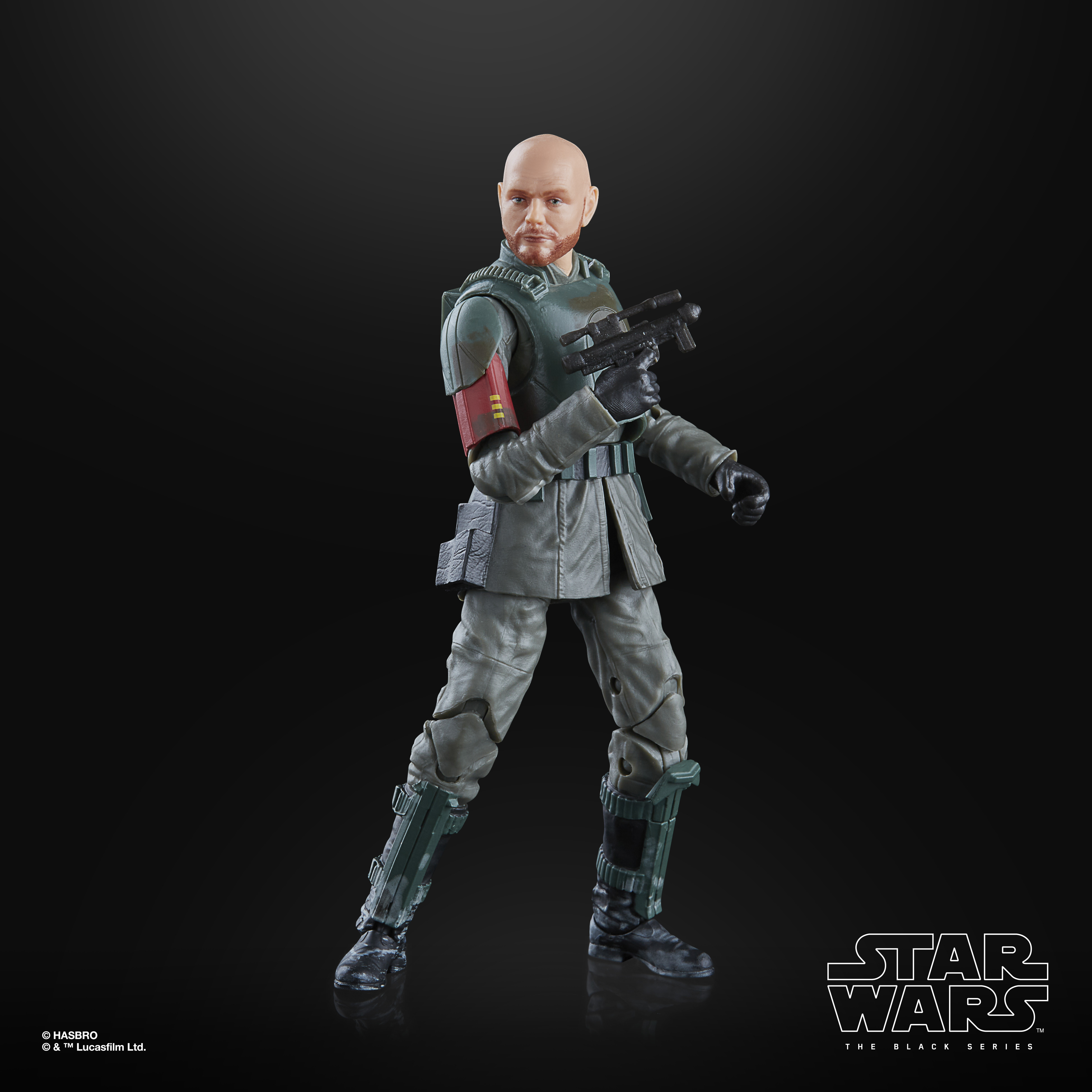 Personaggio di Star Wars in un completo verde e grigio. Il personaggio è calvo e tiene in mano una pistola.
