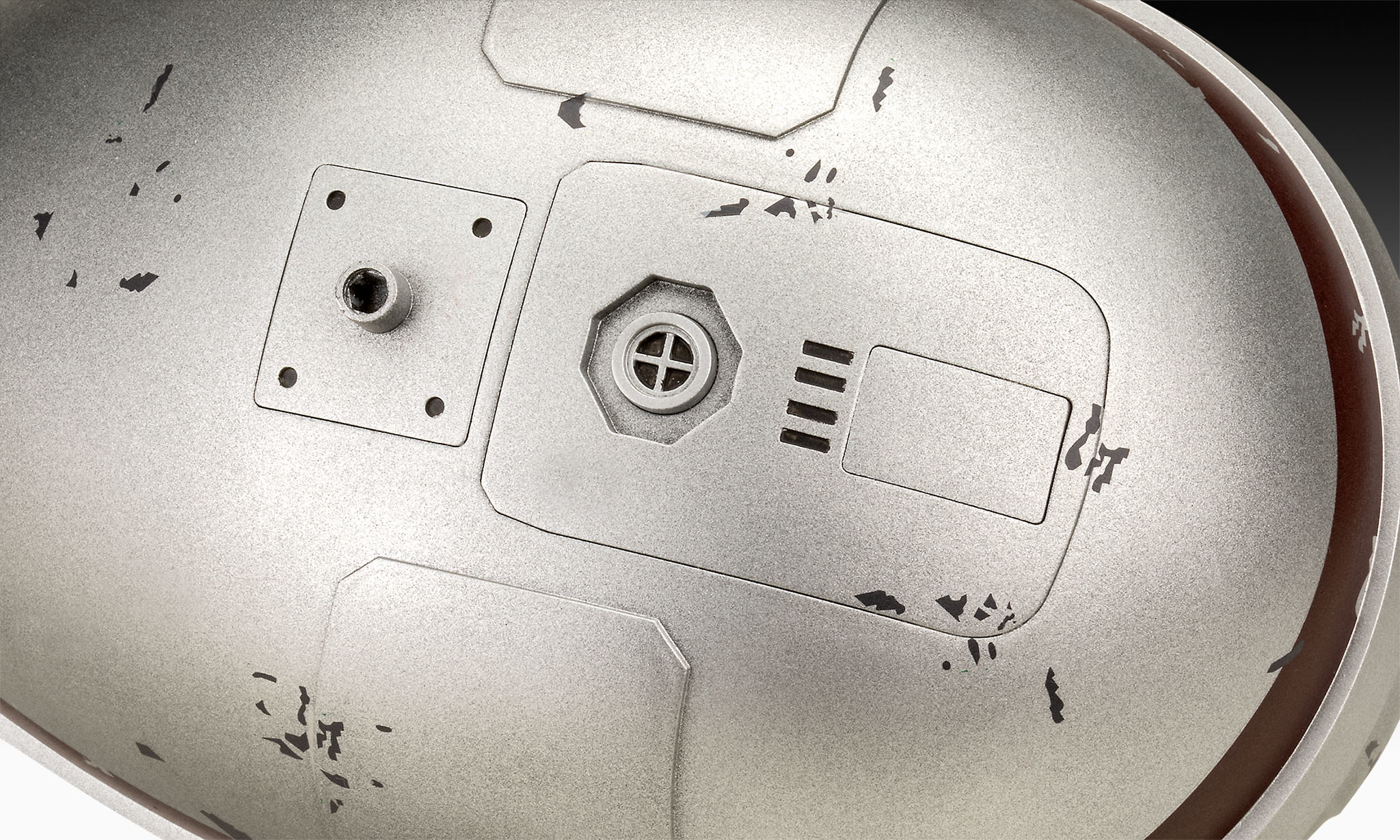 Close-up of a metallic surface with indentations and an opening.