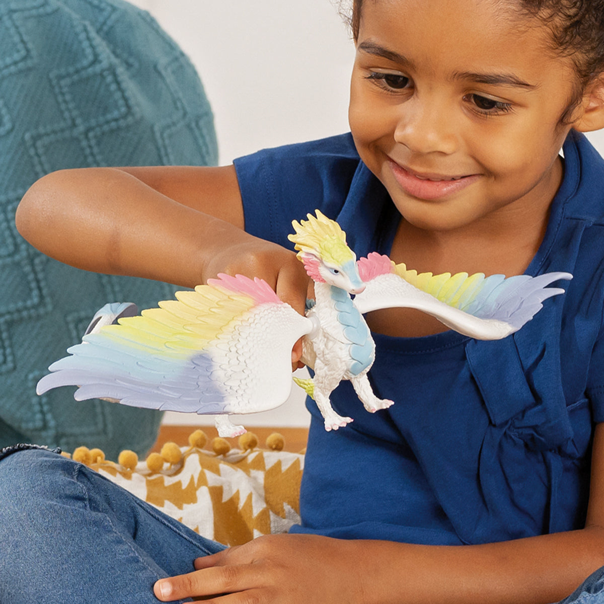 Un bambino che tiene in mano un drago giocattolo colorato. Il drago è multicolore con grandi ali e un corpo bianco.
