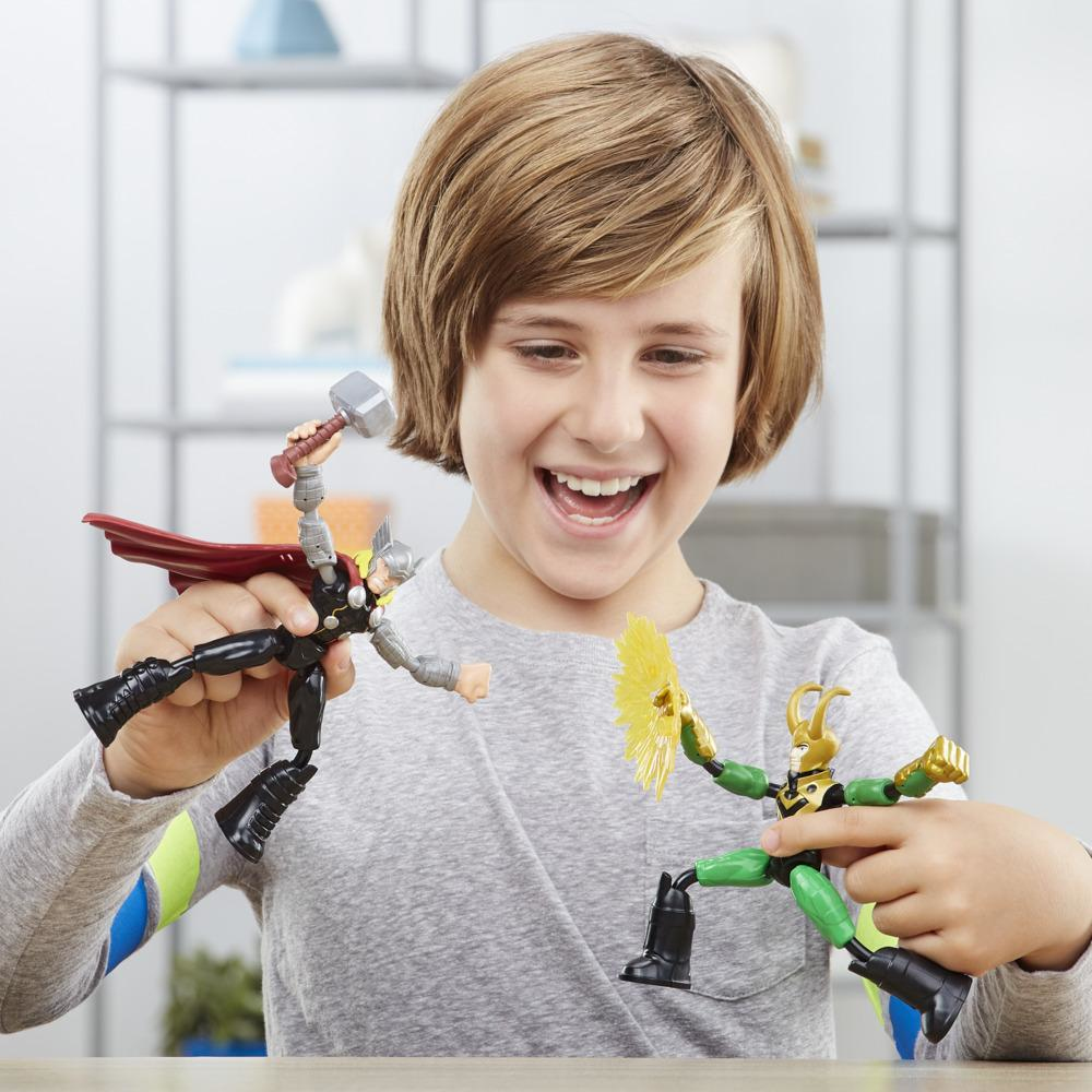 Chłopiec trzymający dwie zginane figurki superbohaterów, Thora i Lokiego, uśmiechający się do kamery.