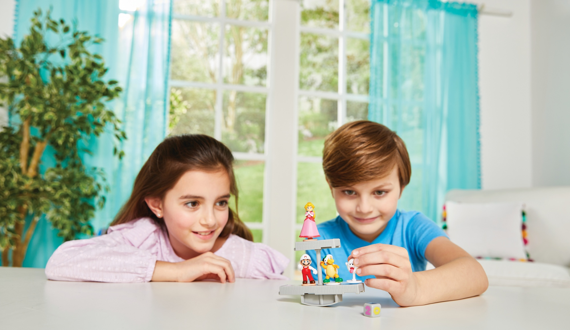 Dwoje dzieci bawiących się zabawką. Na stole stoi wieża zabawek.