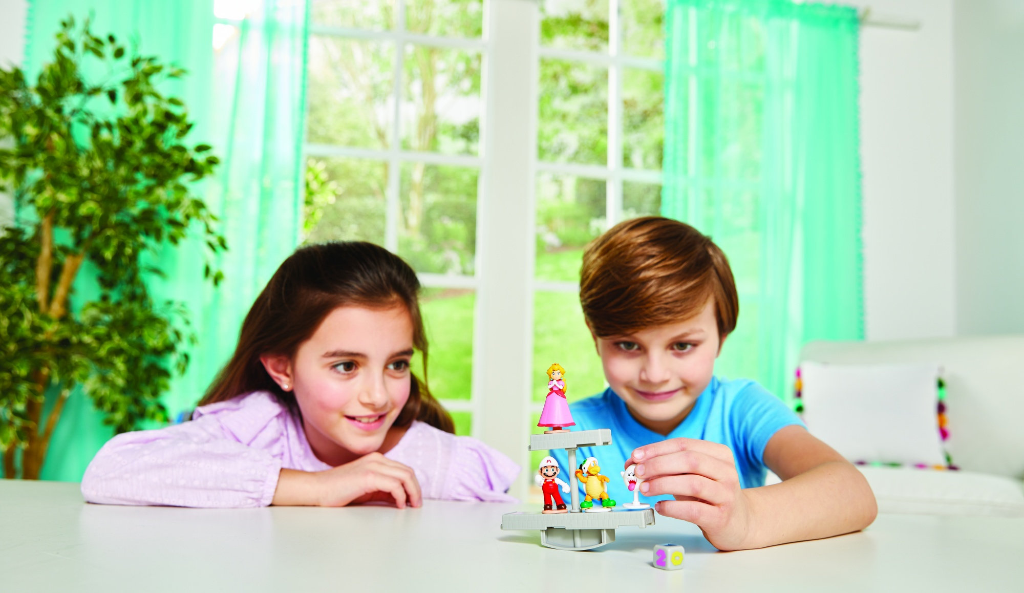 Dwoje dzieci grających w grę równoważną z figurkami na białym stole.