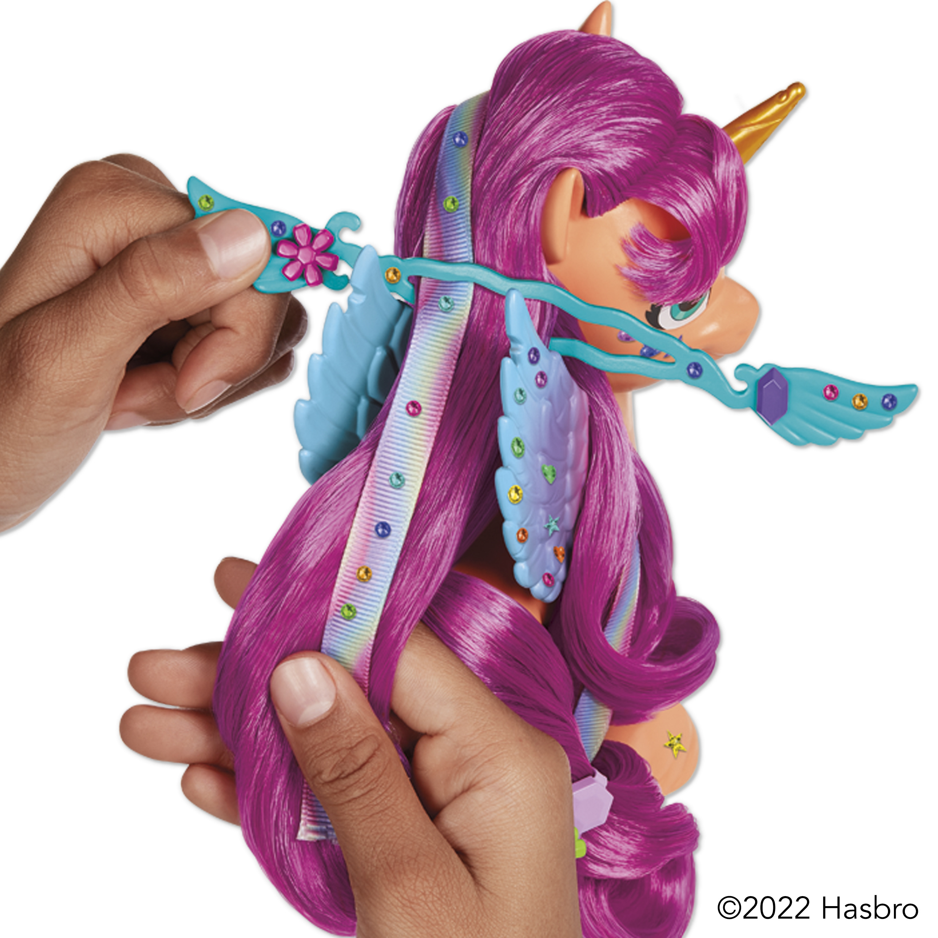 Manos peinando la melena púrpura de un pony de juguete con peine y accesorios.