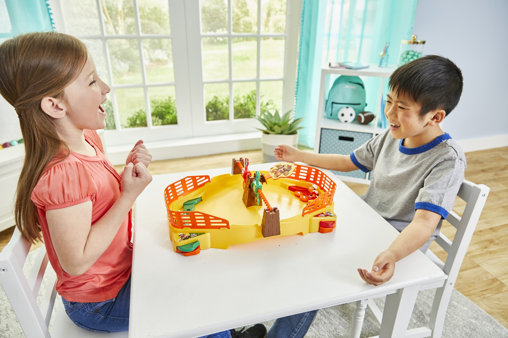 Dos niños jugando un juego de mesa en una mesa, ambos sonriendo y emocionados.