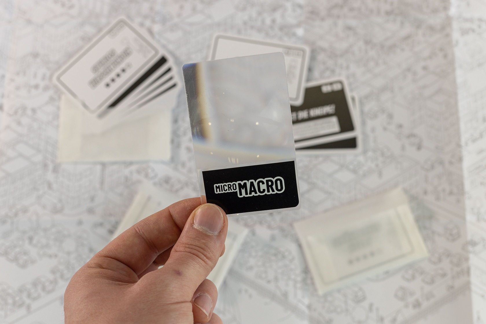 Eine Hand, die eine transparente Karte mit dem Text 'MICRO MACRO' in Schwarz hält.