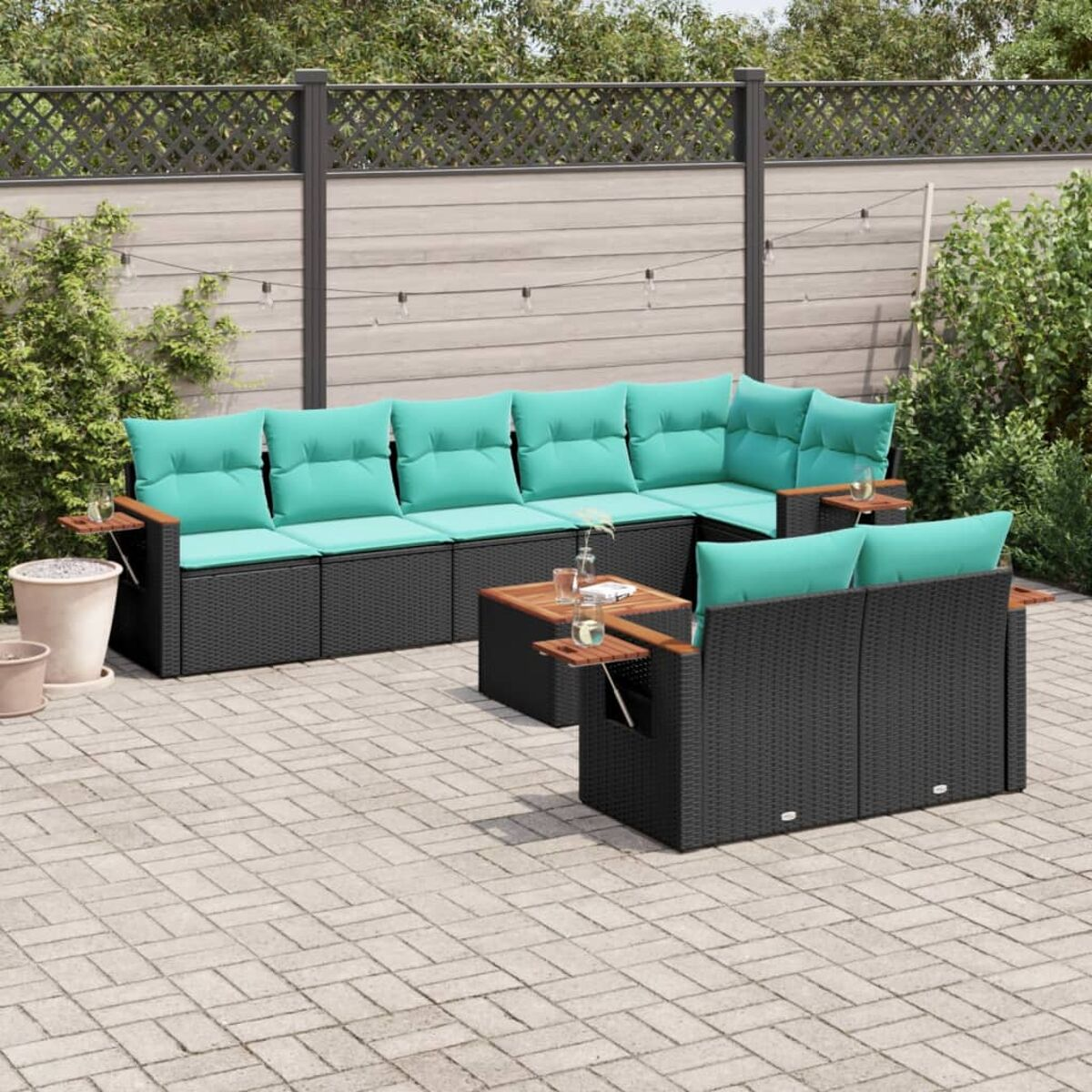 Set da patio esterno con cuscini turchesi, cornici nere e tavolini in legno su un patio in mattoni.