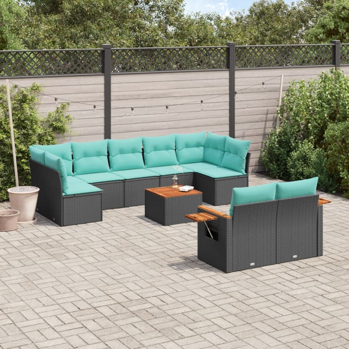 Set da patio esterno con cuscini turchese, struttura grigio scuro, su un patio in mattoni. Recinzione e piante sullo sfondo.