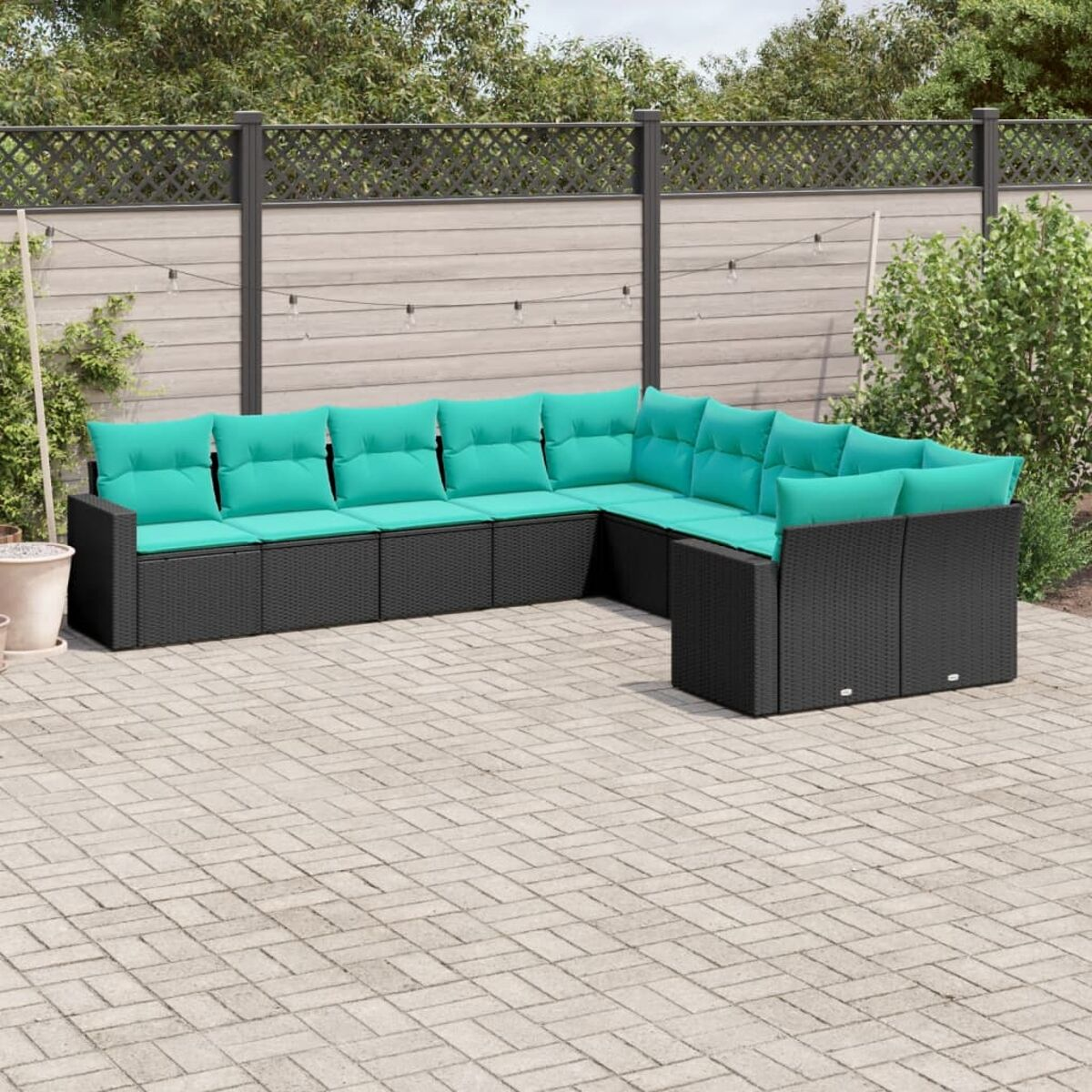 Divano da esterno in vimini nero con cuscini verde acqua su patio pavimentato.