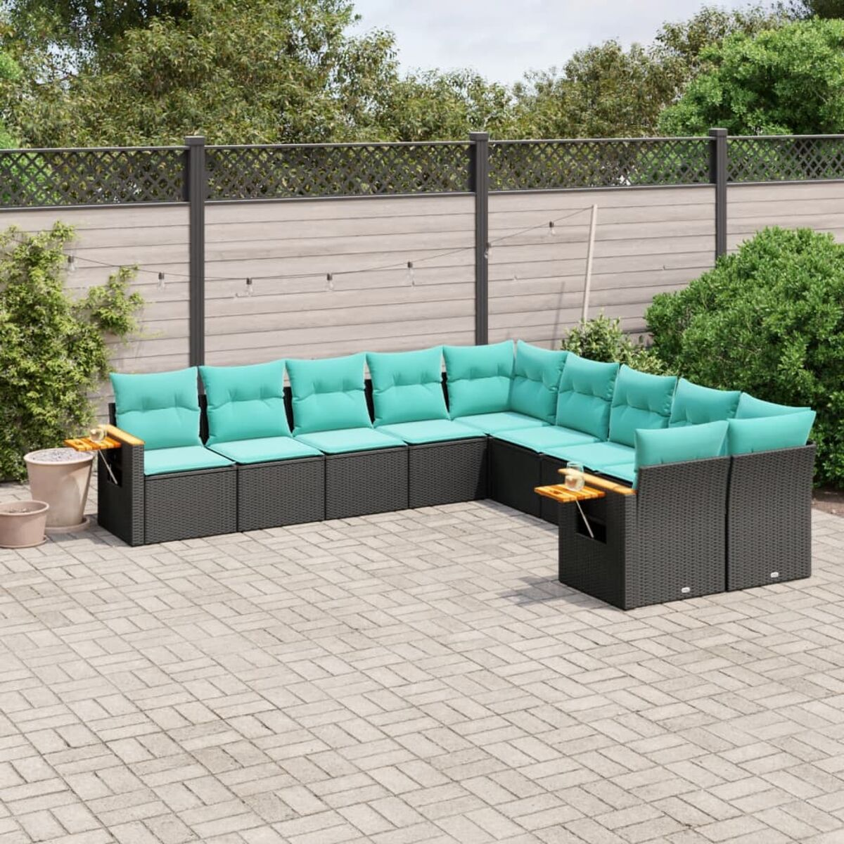 L-förmiges schwarzes Outdoor-Sofa mit türkisfarbenen Kissen, einem hölzernen Beistelltisch und einem Zaun.
