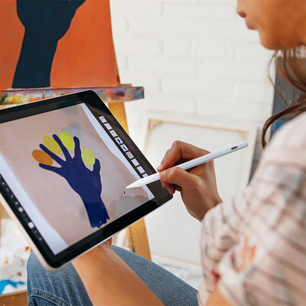 Hände einer Person, die einen Stift auf einem Tablet verwenden, das eine digitale Zeichnung von bunten Formen zeigt.