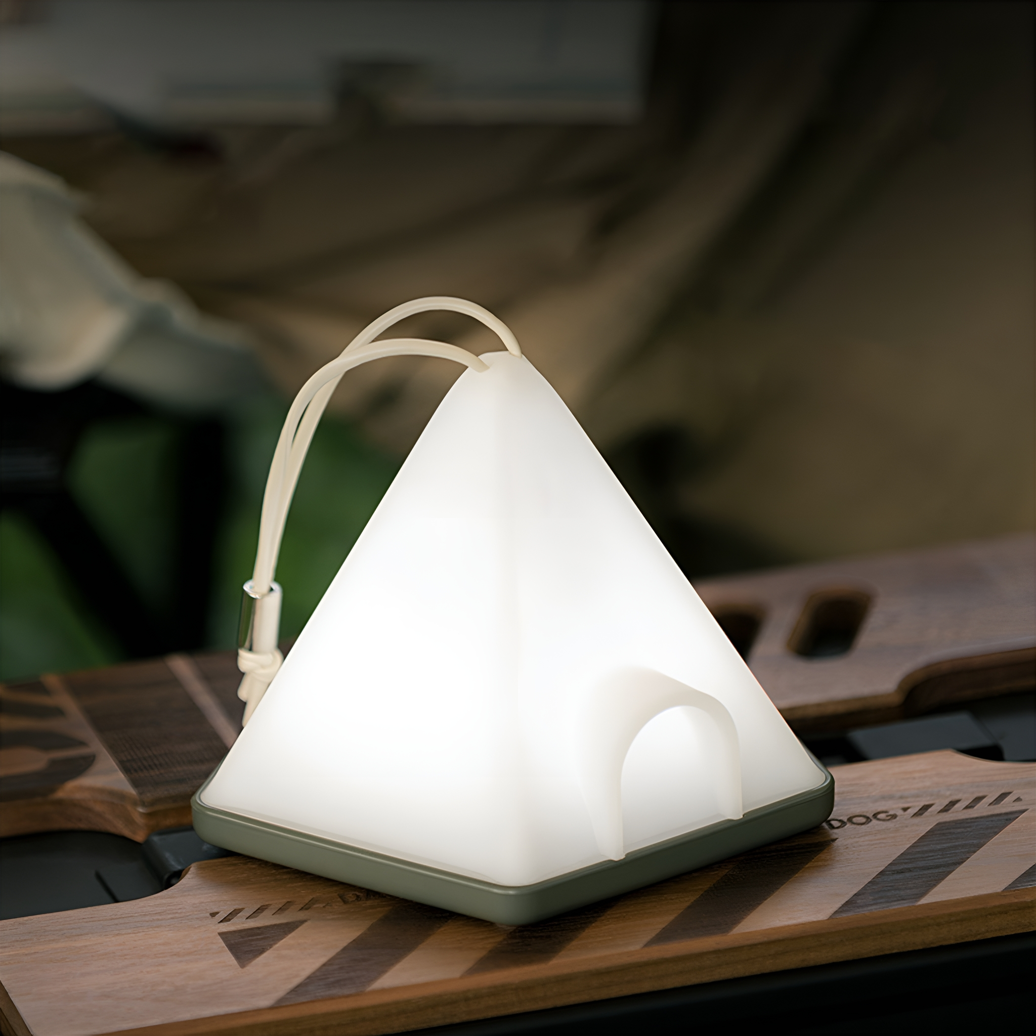 Eine weiße, pyramidenförmige Lampe mit Griff. Sie steht auf einer Holzoberfläche.