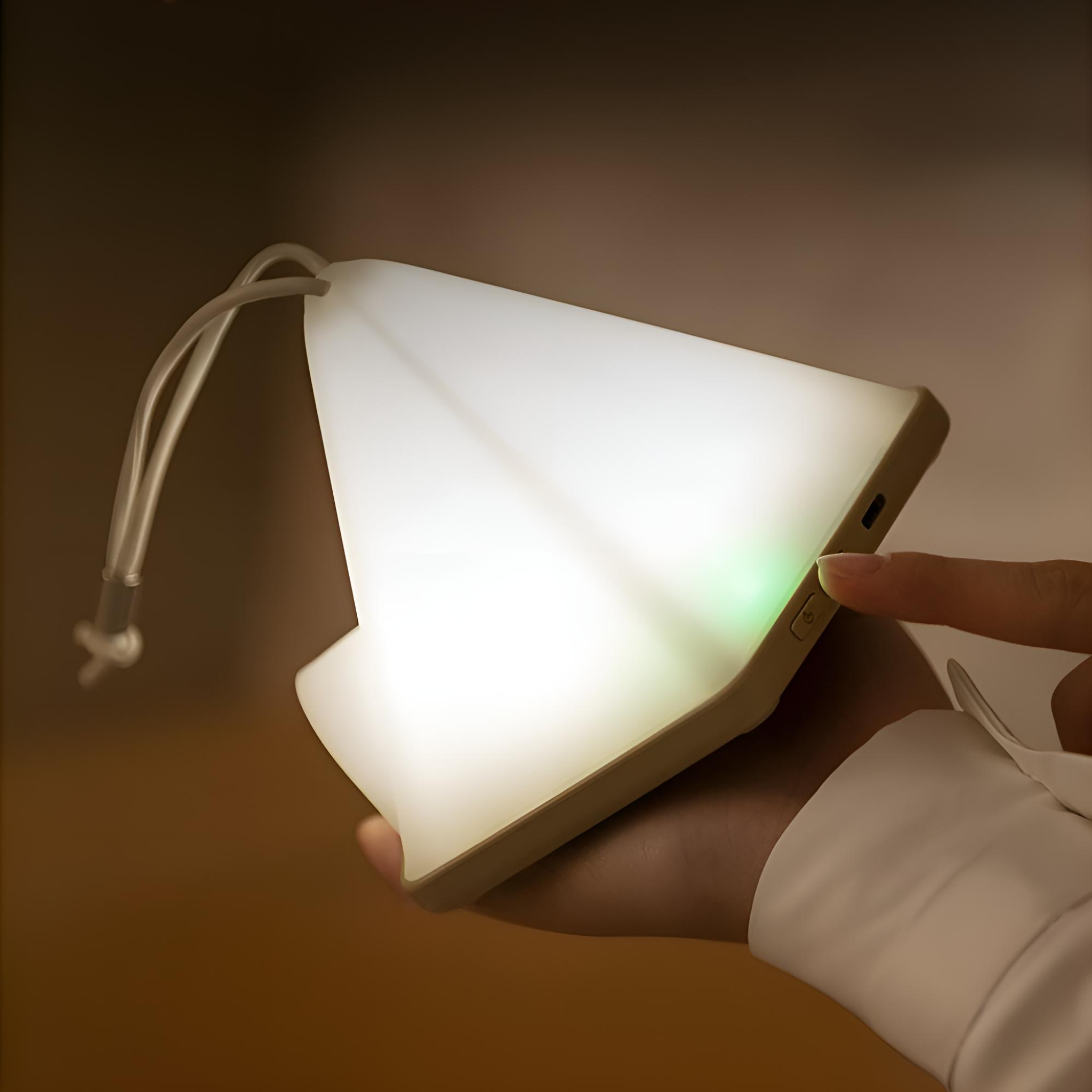 Weisse, dreieckige Lampe, die Licht aussendet, von einer Hand gehalten. Hand drückt Knopf. Dunkler Hintergrund.