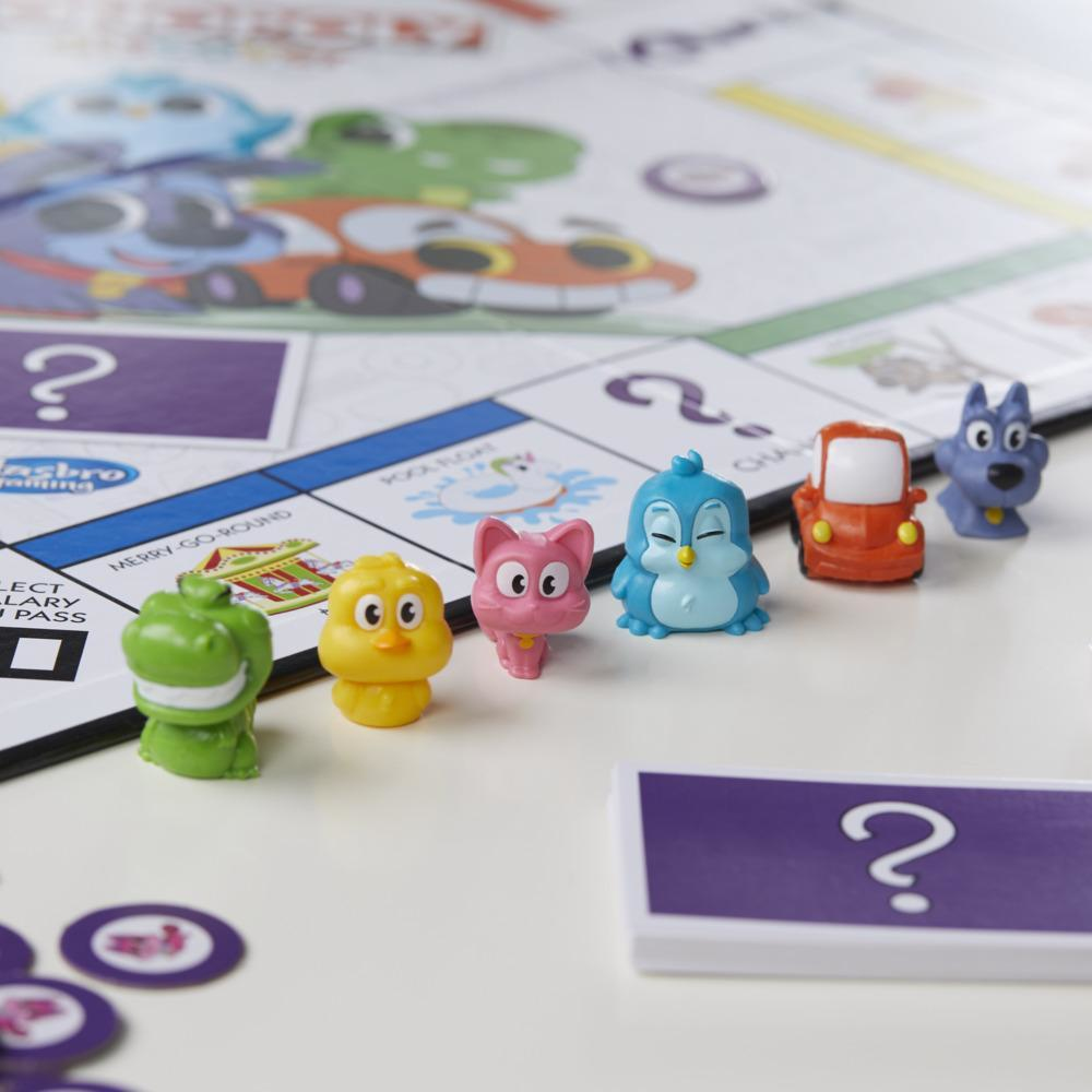 Monopoly-Brett mit bunten Spielfiguren. Auto-, Hunde-, Vogel-, Katzen- und Dinosaurierfiguren, mit dem Brett im Hintergrund.