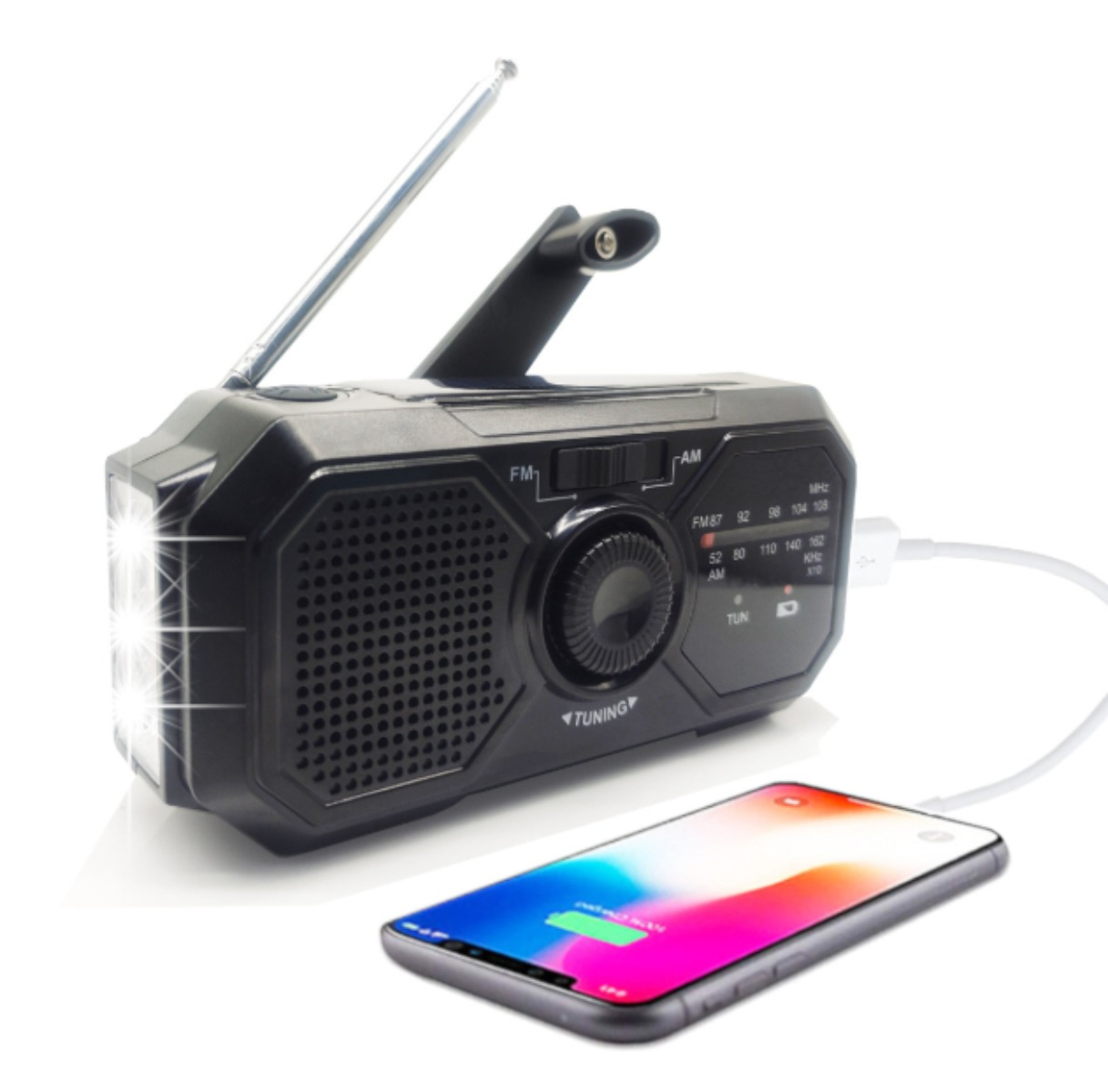 Schwarzes Notfallradio mit Taschenlampe und Telefon, das über ein USB-Kabel geladen wird. Weißer Hintergrund.