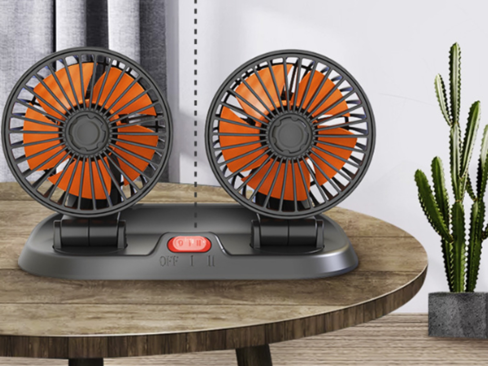 Zwei schwarze Ventilatoren mit orangefarbenen Flügeln auf einem Holztisch. Rechts ist ein Kaktus im Topf zu sehen.