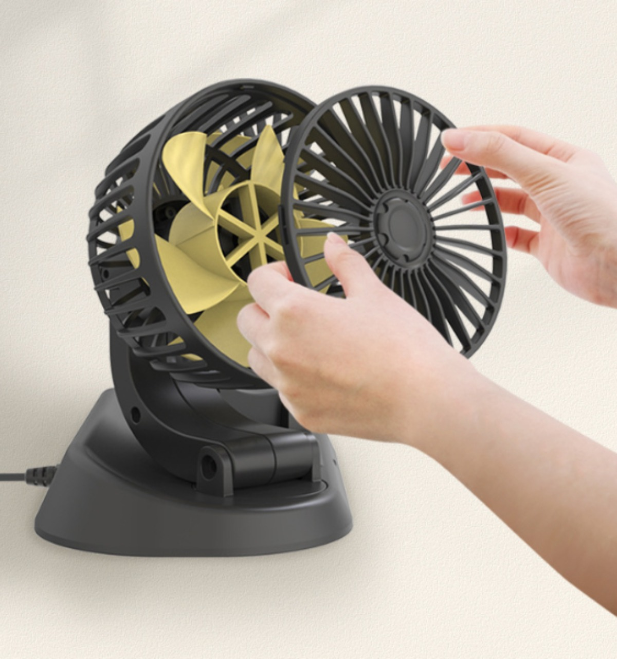 Ein kleiner schwarzer Ventilator mit einem gelben Ventilator im Inneren, der von einer Hand auf weißem Hintergrund montiert wird.