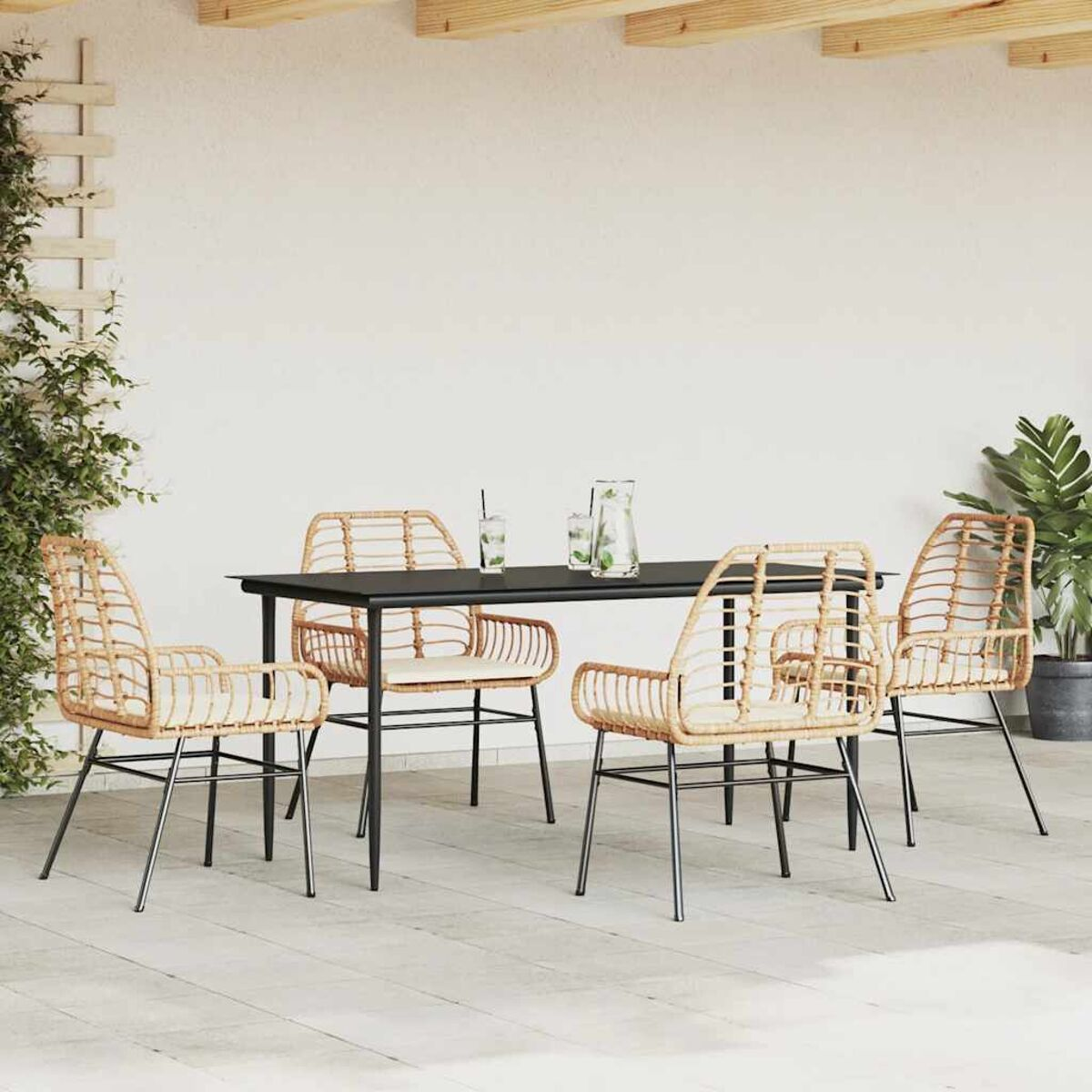 Un set da pranzo all'aperto con un tavolo nero e sedie in rattan su un patio.