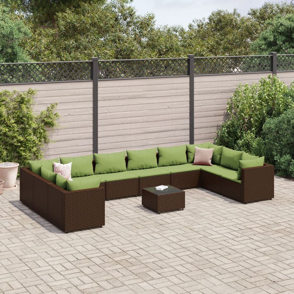 Ein Outdoor-Ecksofa mit grünen Kissen und einem kleinen quadratischen Tisch auf einer Terrasse aus Ziegeln.