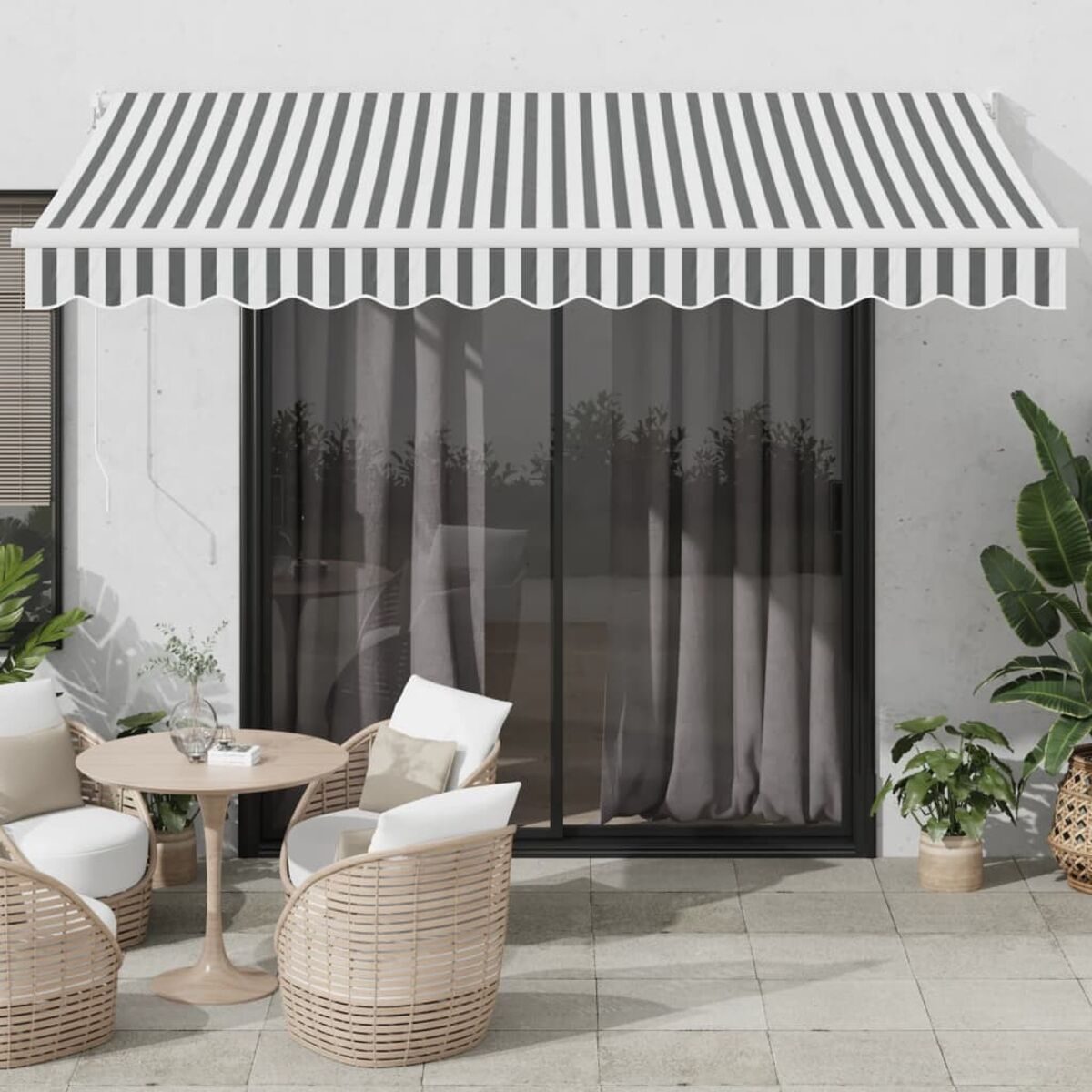 Un patio con tenda a strisce, tavolo, sedie, piante e una porta scorrevole in vetro.