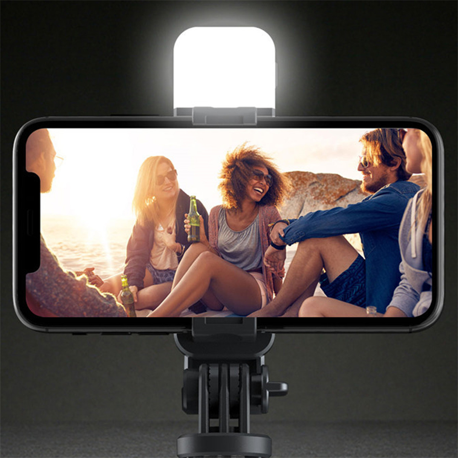 Ein Smartphone zeigt eine Gruppe von Menschen am Strand, beleuchtet von einem am Telefon montierten Licht.