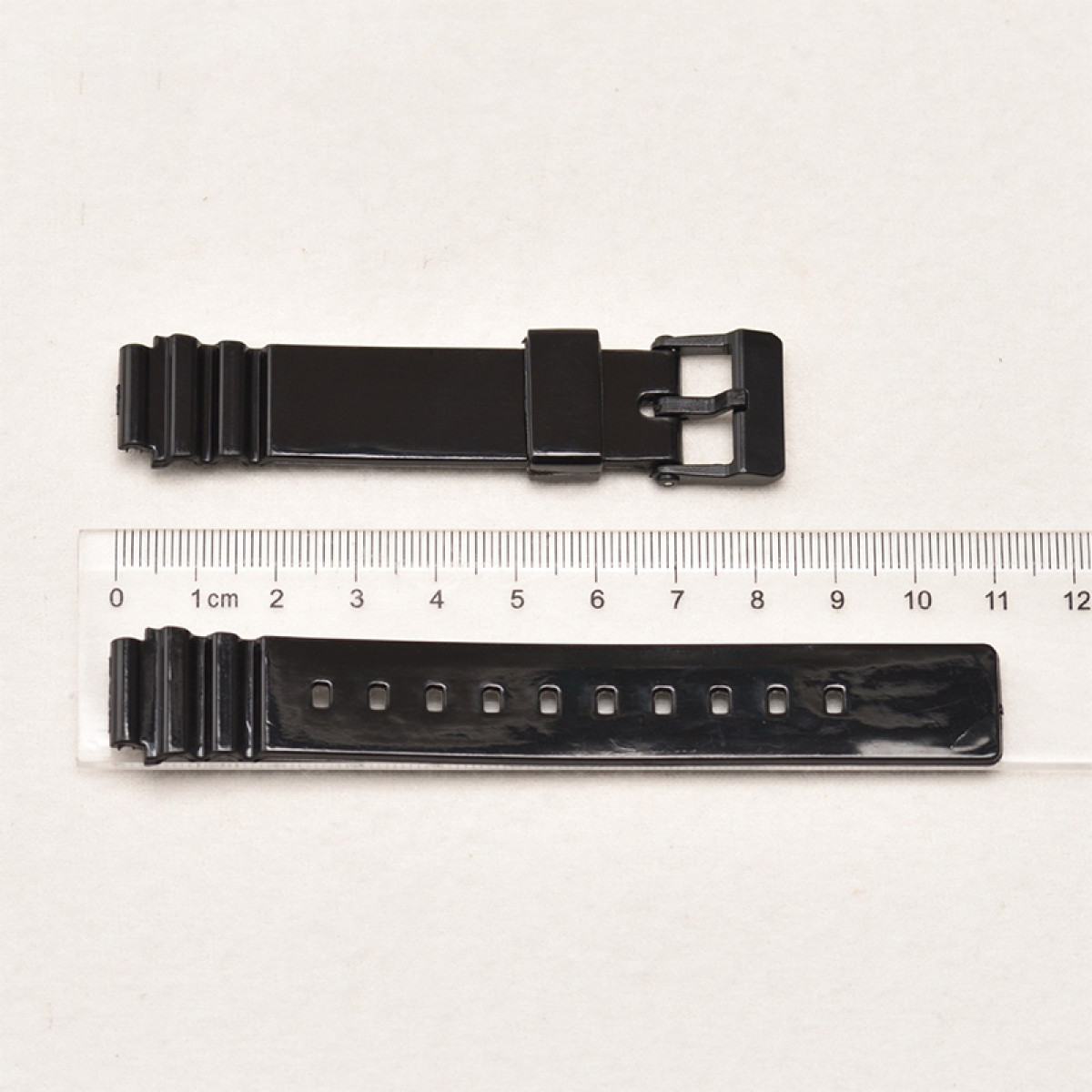 Zwei schwarze Uhrenarmbänder und ein Lineal. Eines hat eine Schnalle, das andere Löcher für die Schnalle.